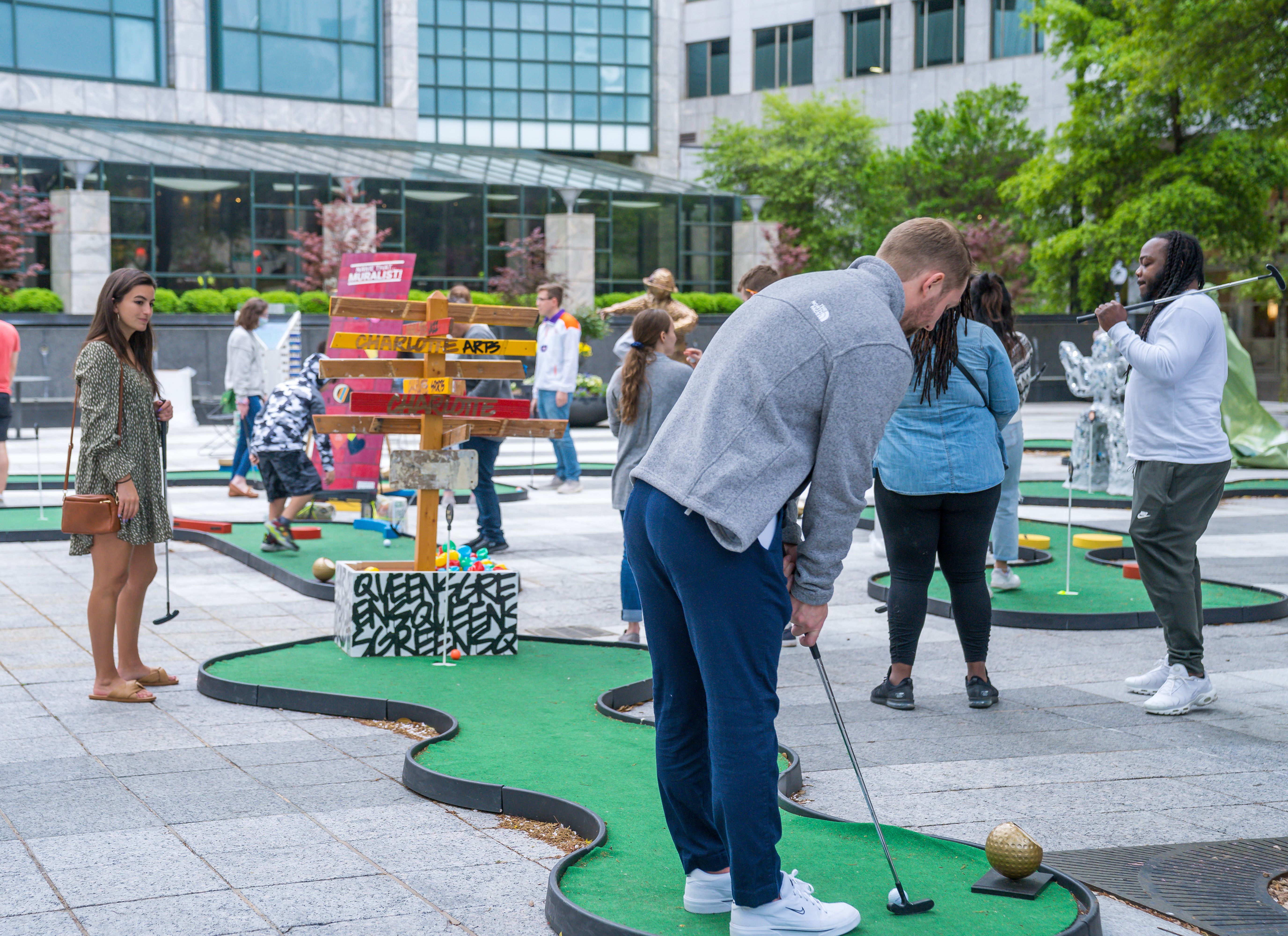 people play putt-putt golf in a city plaza