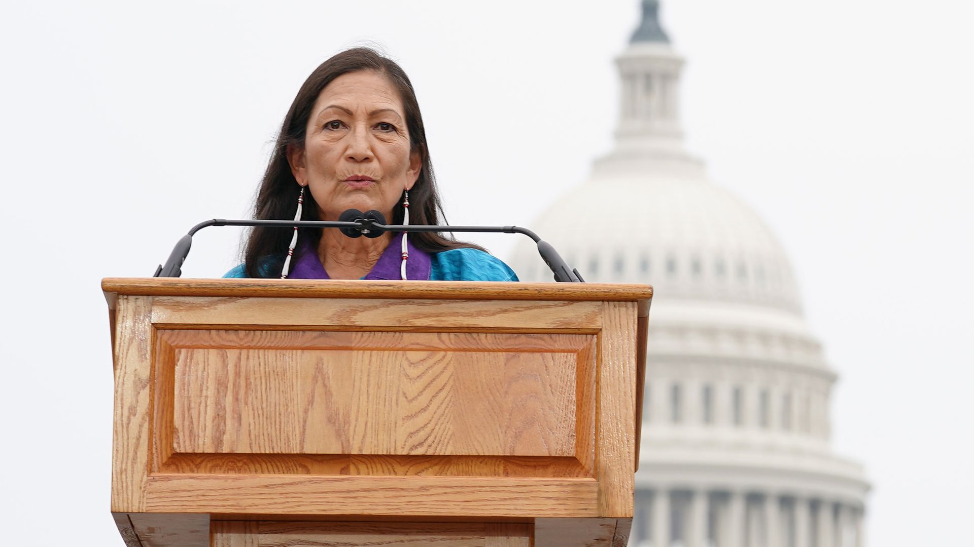 Photo of Deb Haaland speaking from a podium in front of the U.S. Capitol