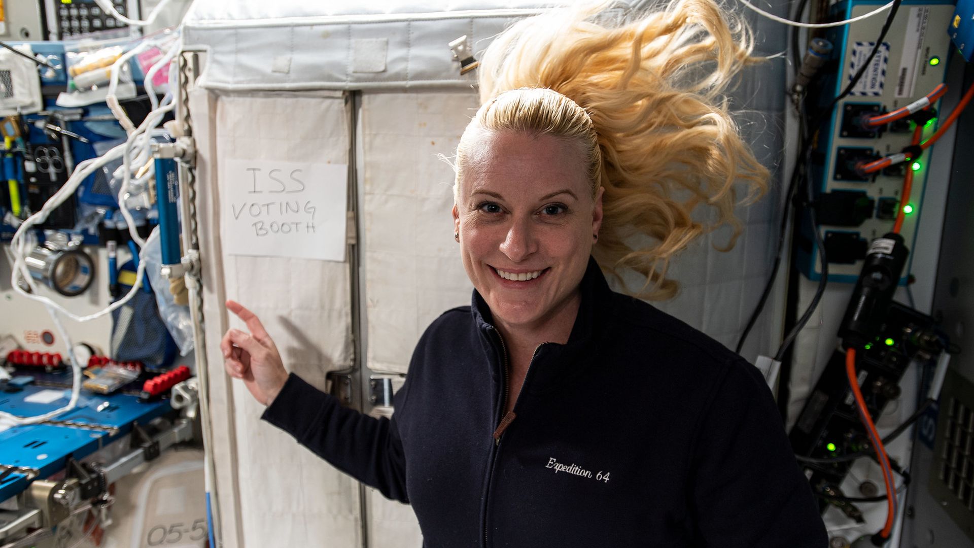 Astronaut Kate Rubins floats next to a door that says 