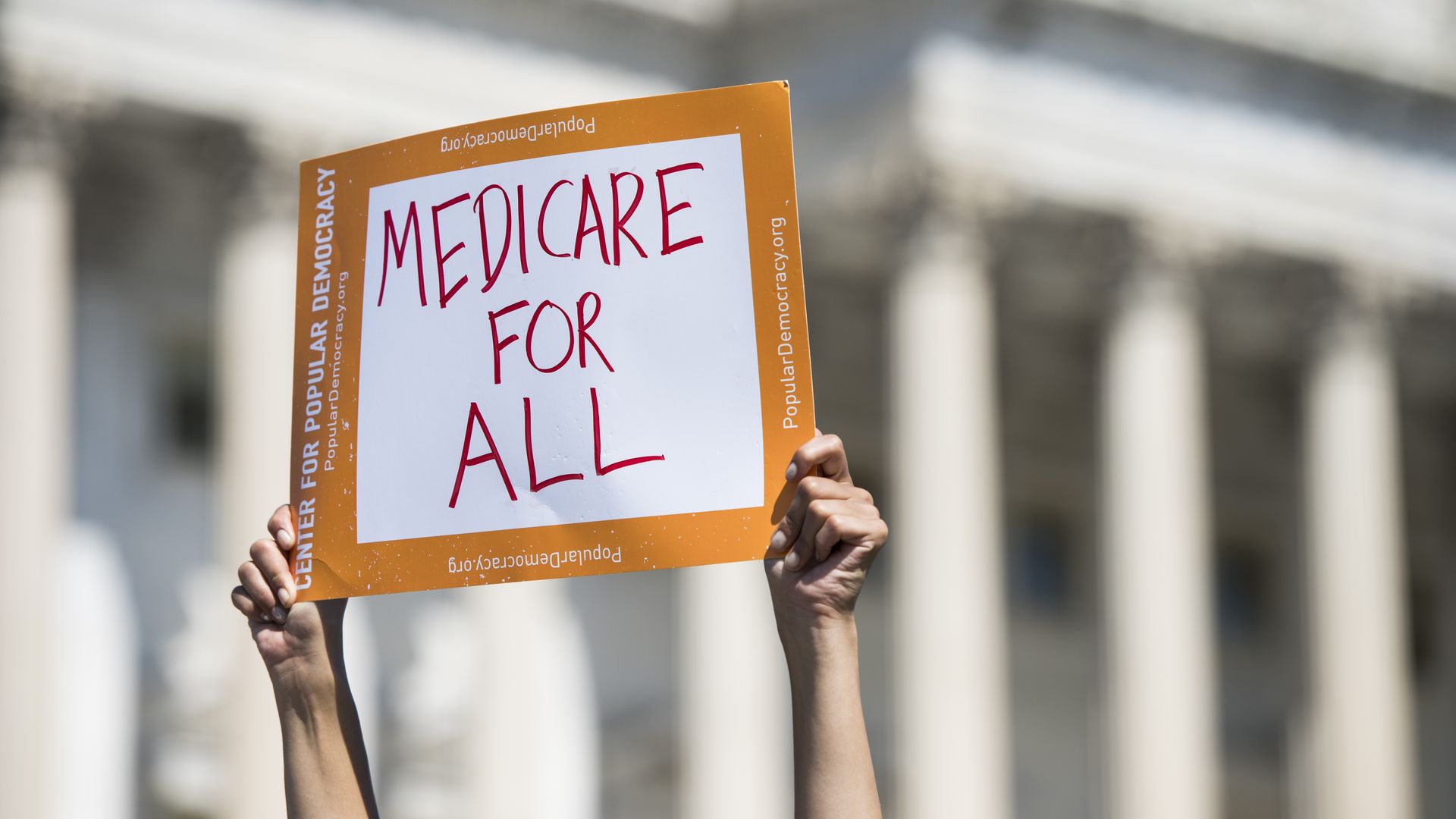 In this image, a demonstrator holds a sign that reads "Medicare for All." 