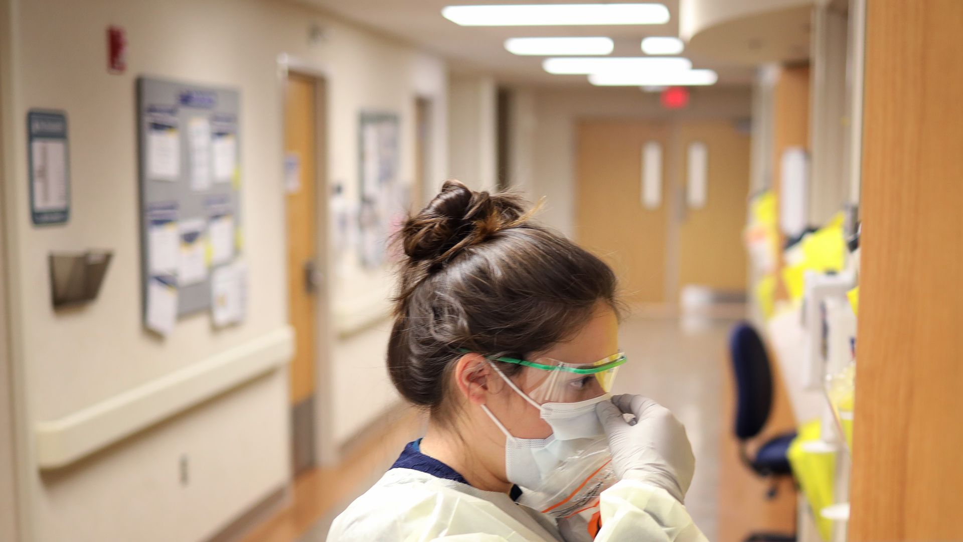 A nurse wearing a face mask standing in an intensive care unit.