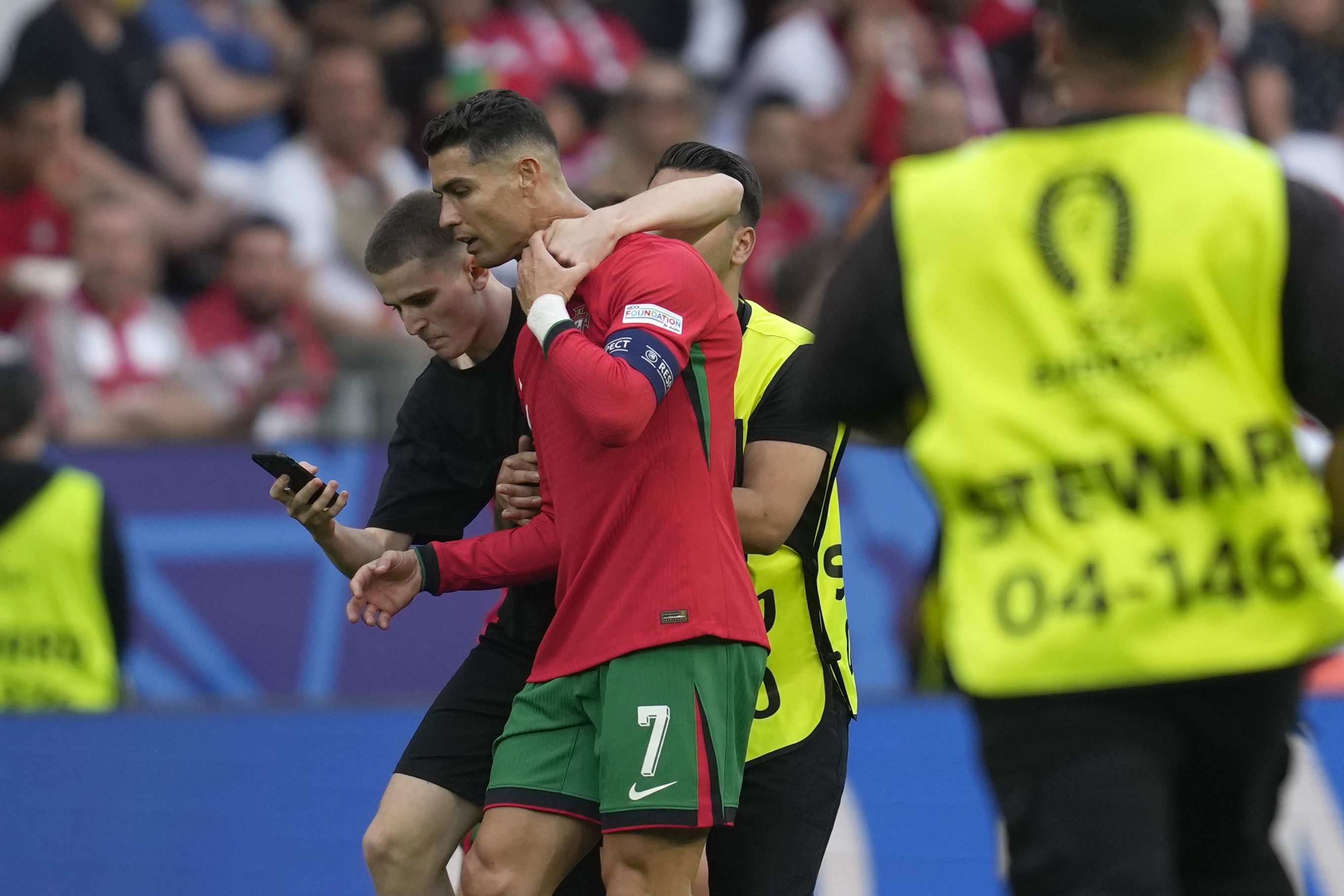 A pitch invader tries to take a selfie with Portugal's Cristiano Ronaldo as a steward moves him out during a Group F match between Turkey and Portugal at the Euro 2024 soccer tournament in Dortmund, Germany, Saturday, June 22