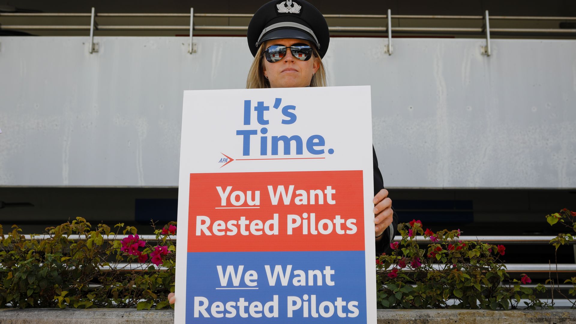 A pilot holding a sign that reads "You Want Rested Pilots/We Want Rested Pilots"
