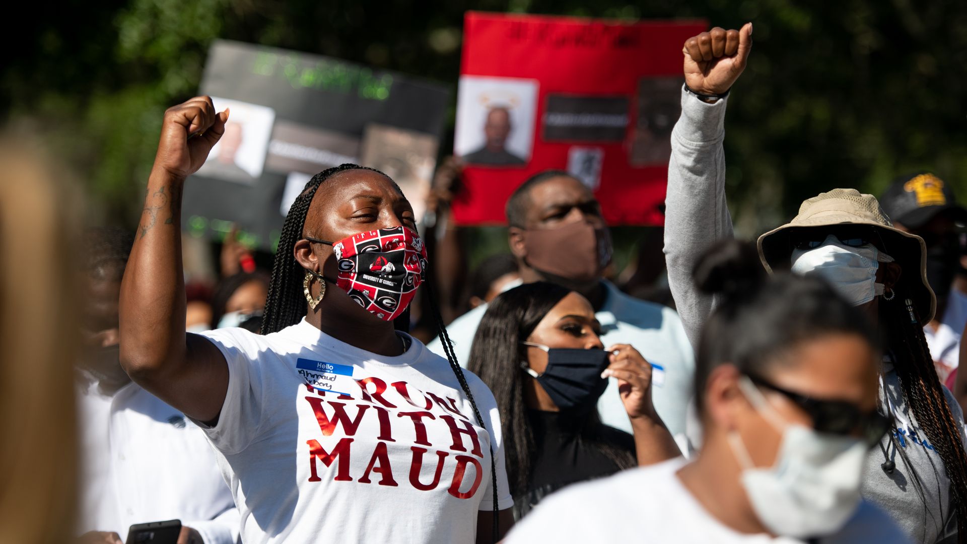 In this image, people stand with T-shorts that say "I run with Maud"