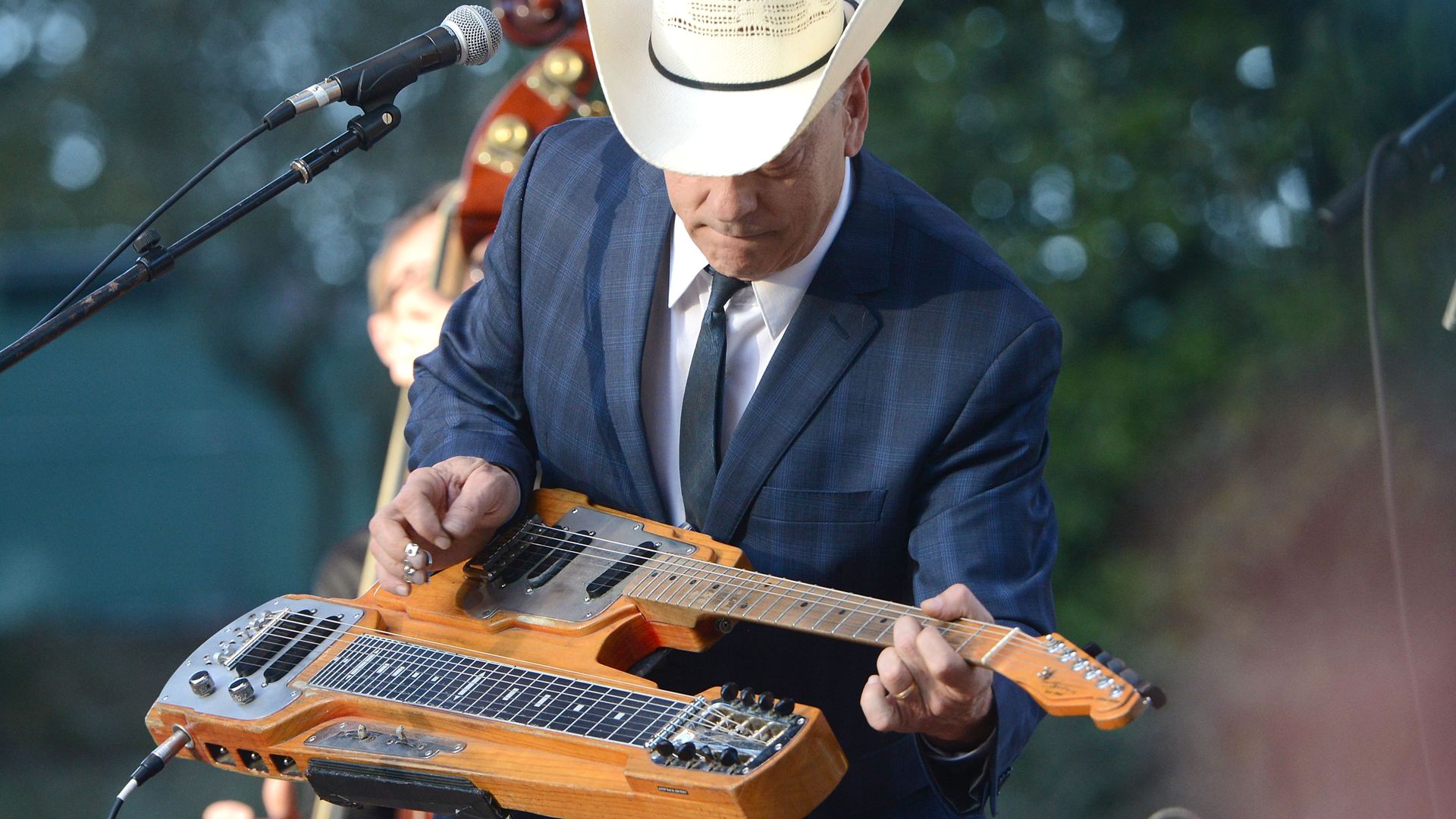 Photo of Junior Brown in a white cowboy hat performing on a stage