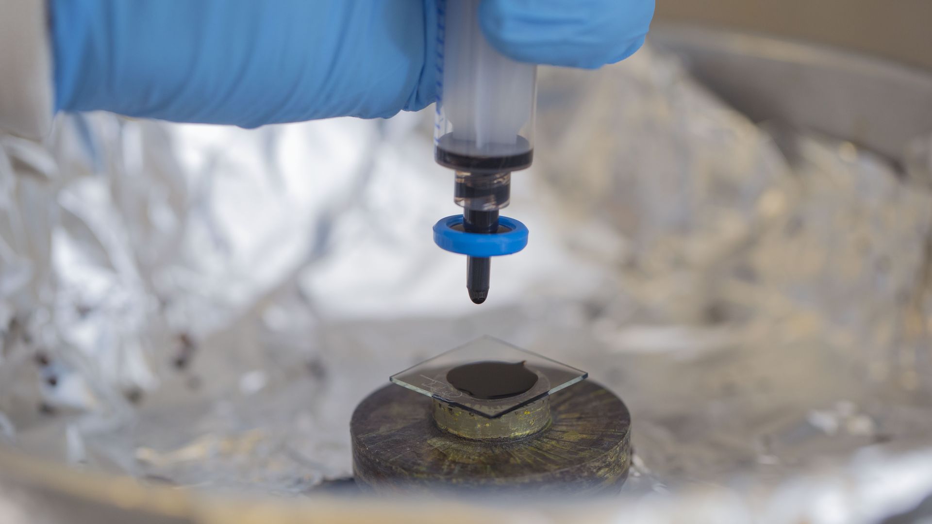 lab scientist coating a glass slide with indium