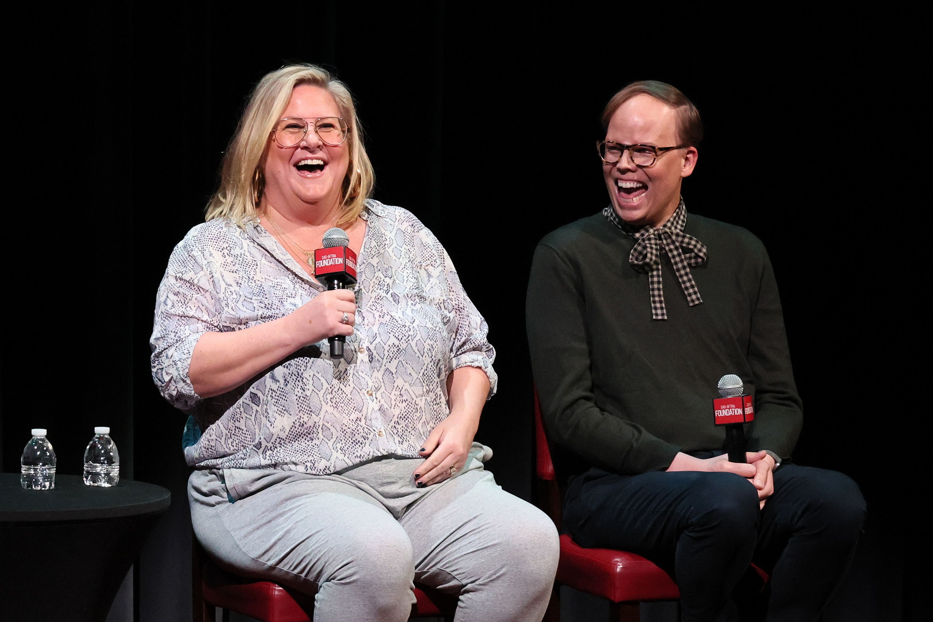 Photo of two people with microphones laughing 
