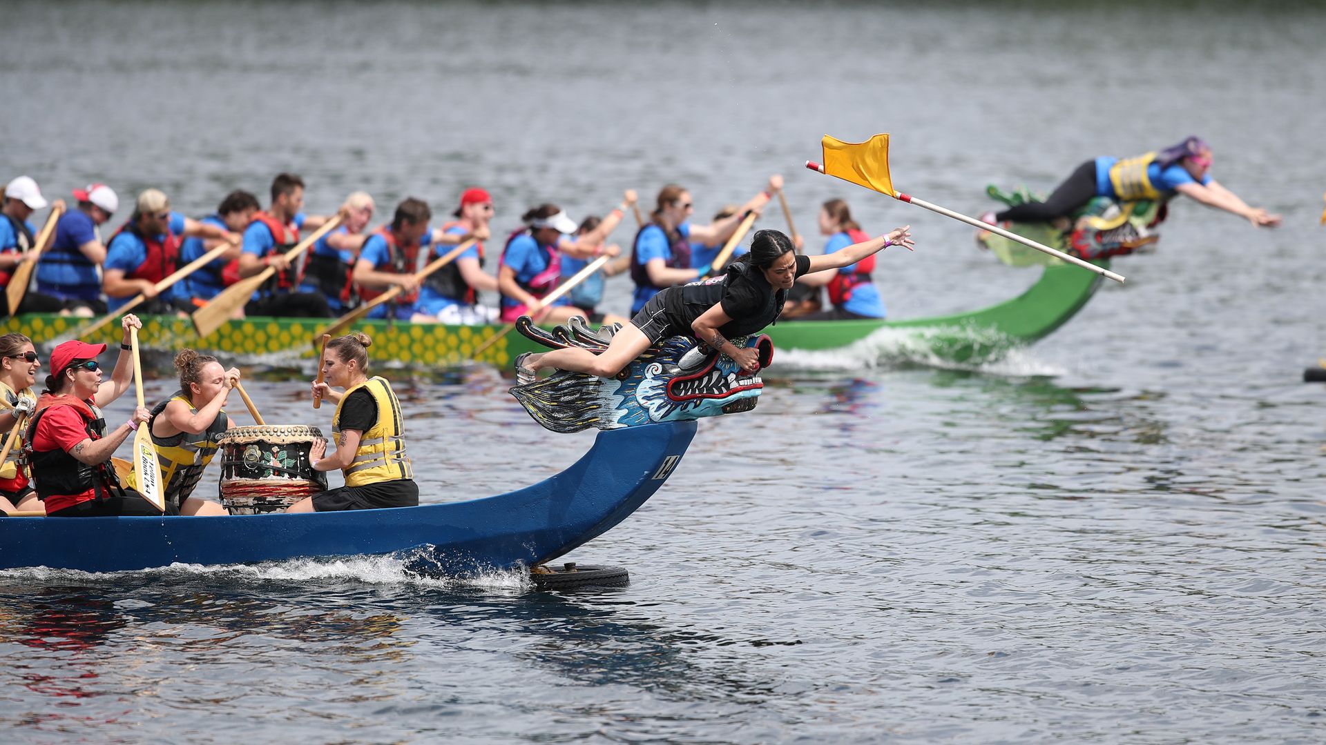 A group of people on dragon-shaped boats racing across a lake.