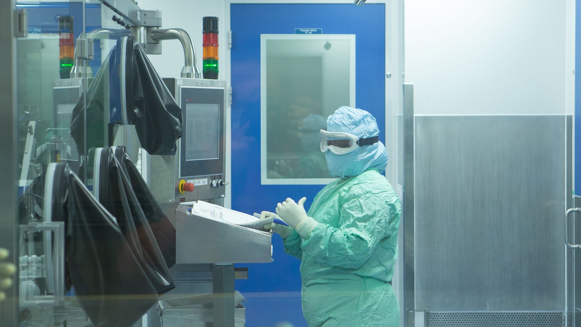 Photo of a person in a hazmat suit operating a manufacturing station