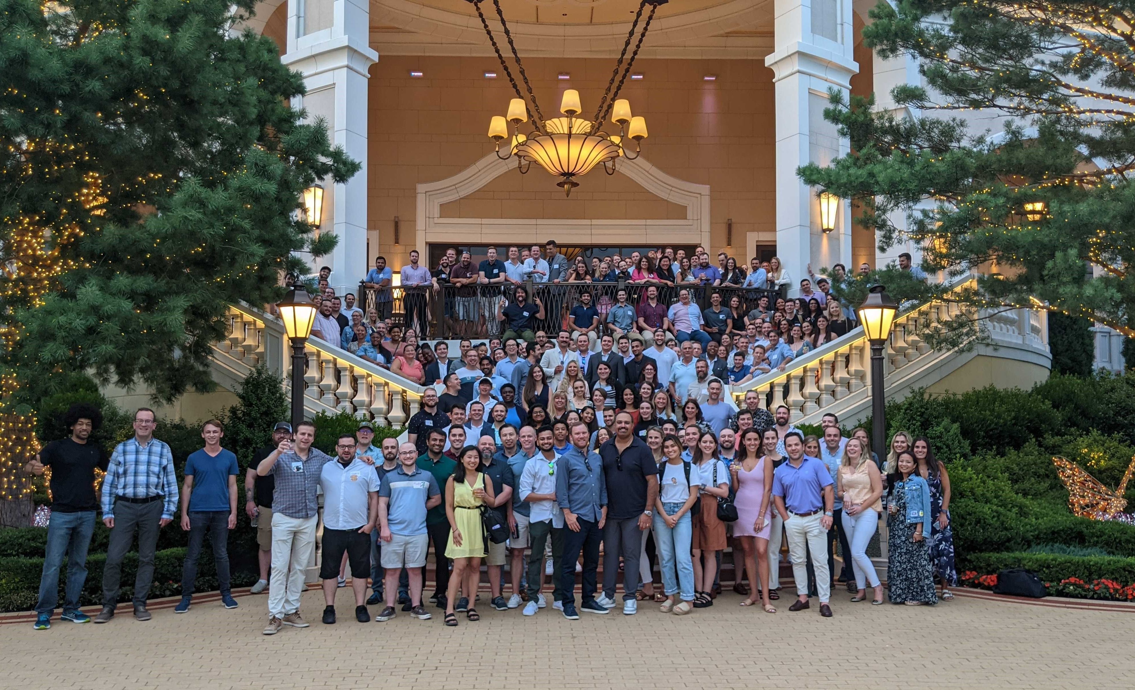 A large group of people standing outside of a building. They are all facing the camera. 