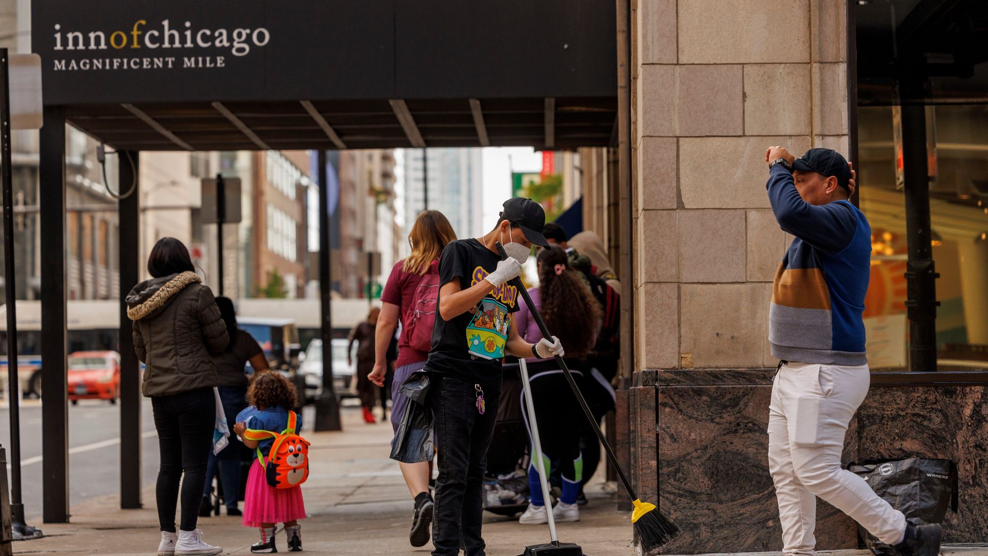 Photo of a man sweeping the sidewalk outside of a migrant shelter