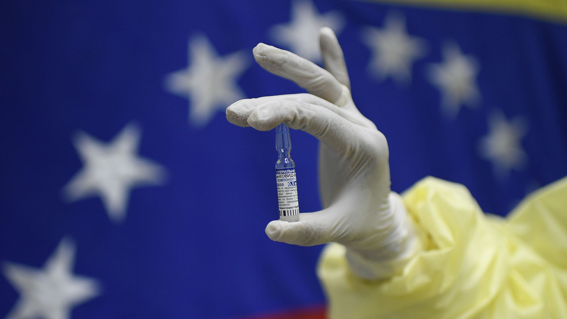 Picture of Russian vaccine vial in front of a Venezuelan flag