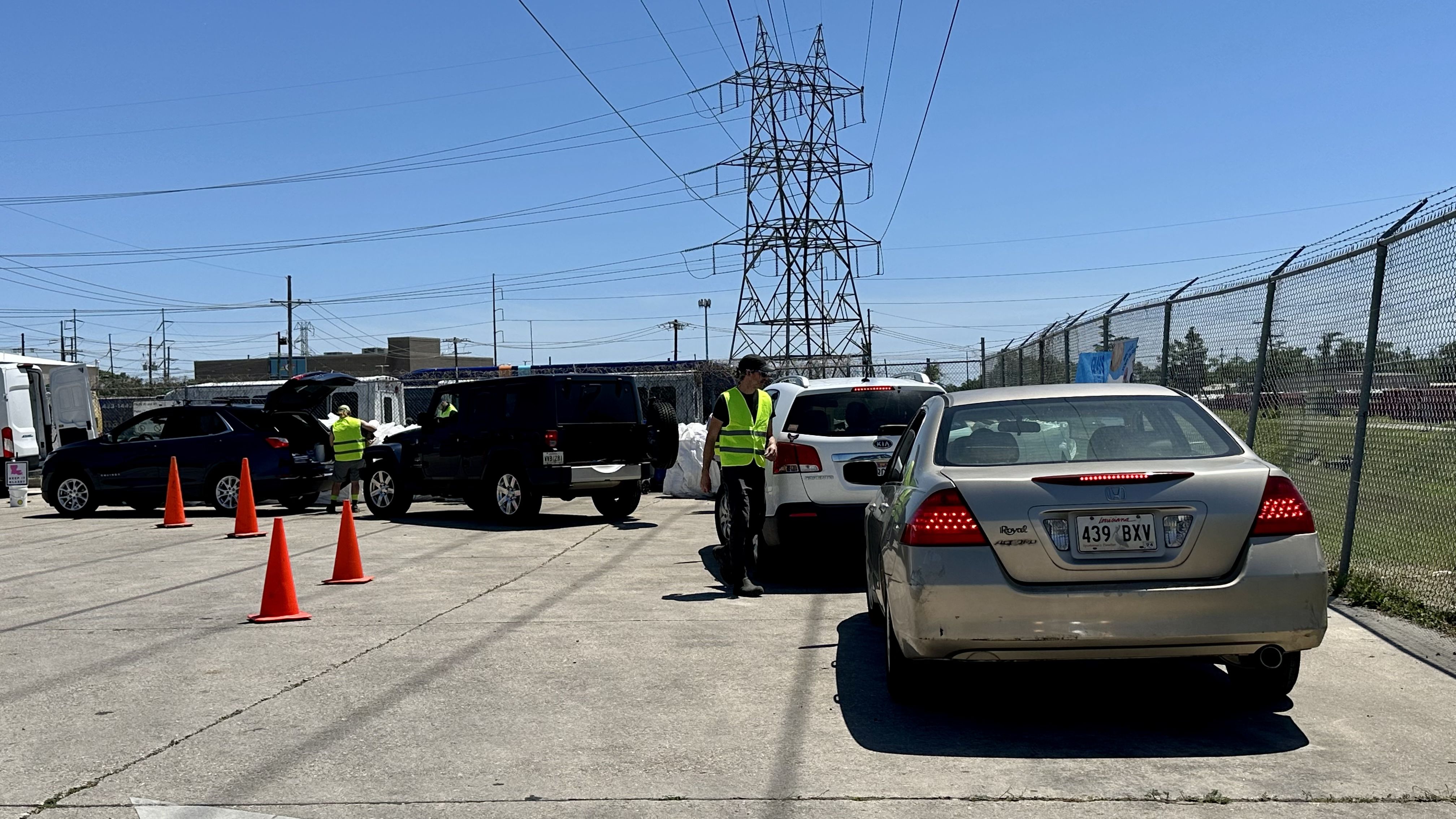 Photo shows cars in line and people walking around in neon yellow vests.