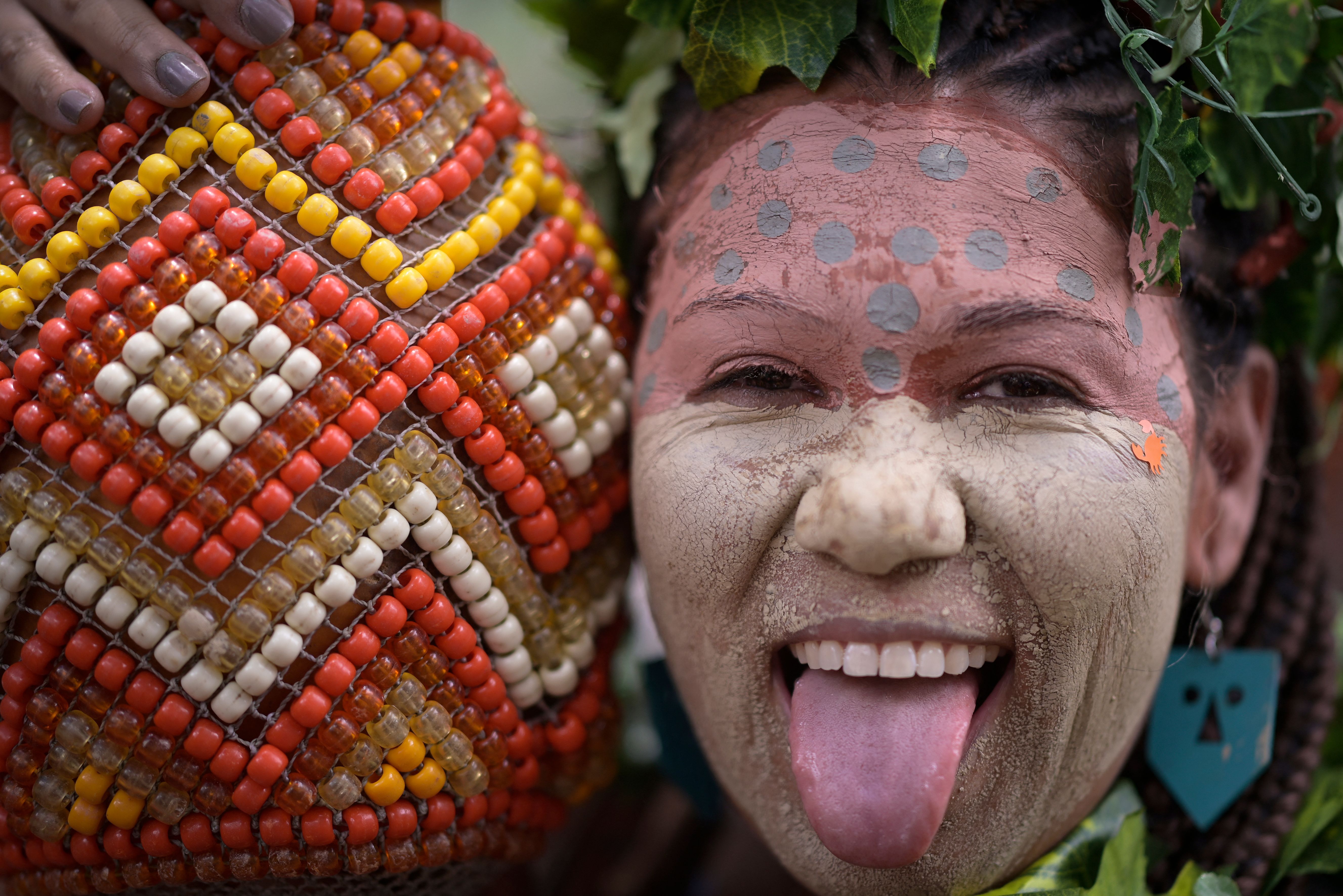 A woman with face paint smiles with her tongue out 