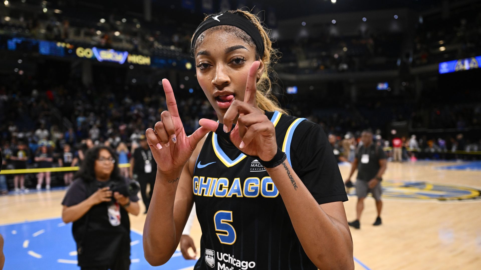 Photo of a female basketball player making a "W" gesture for winning during a game. 
