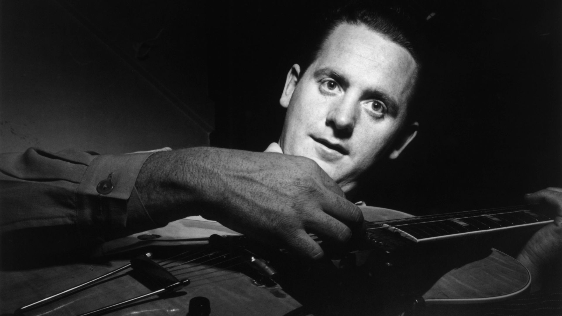 A black-and-white photo of guitar pioneer Les Paul playing electric guitar.