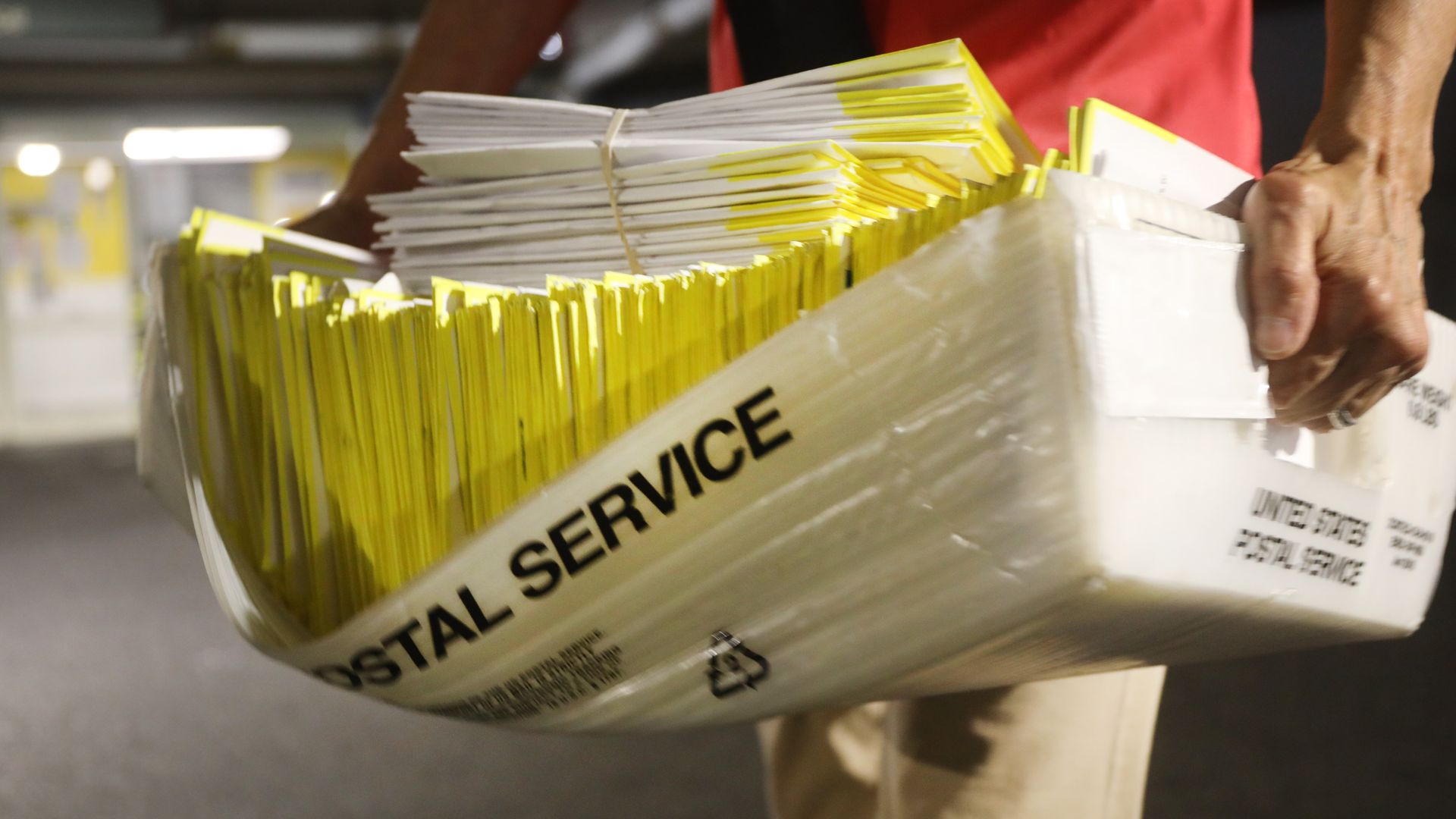 A polling worker holds 2020 presidential primary ballots that were dropped at a post office