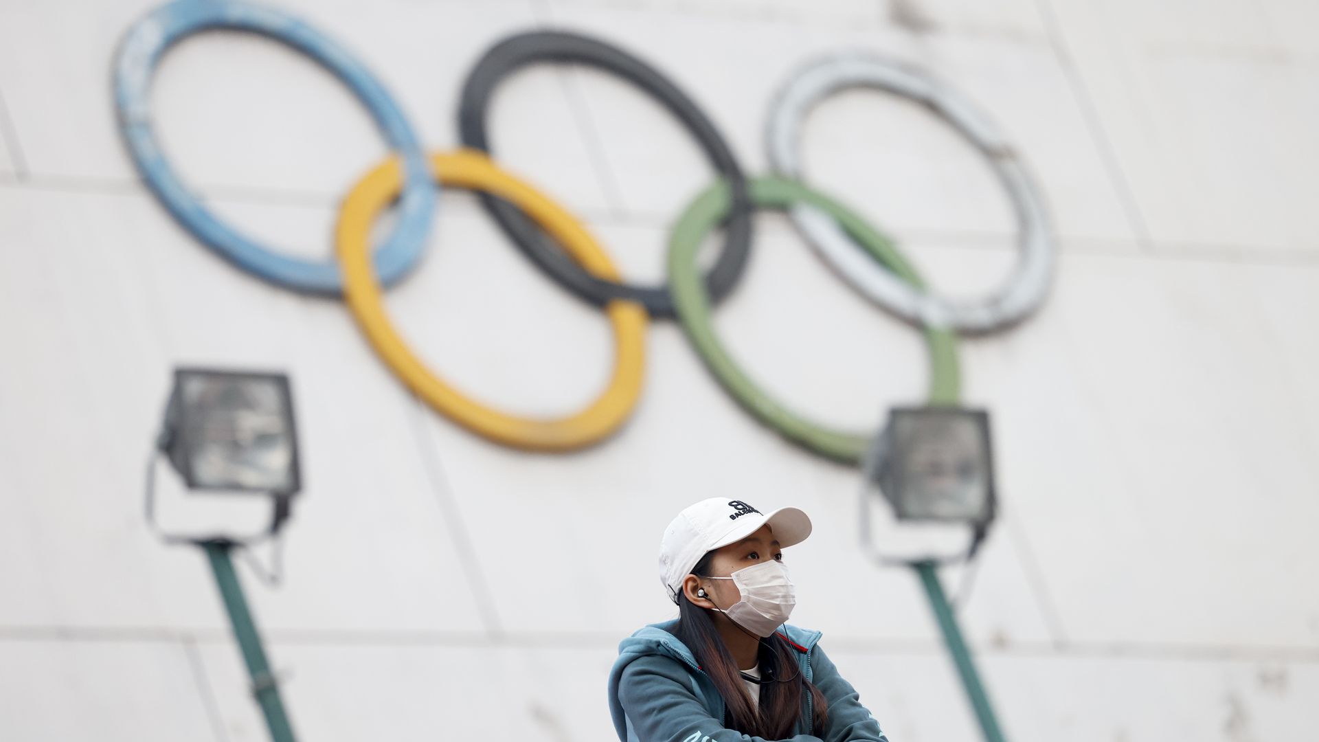 A woman wearing a face mask stands in front of 