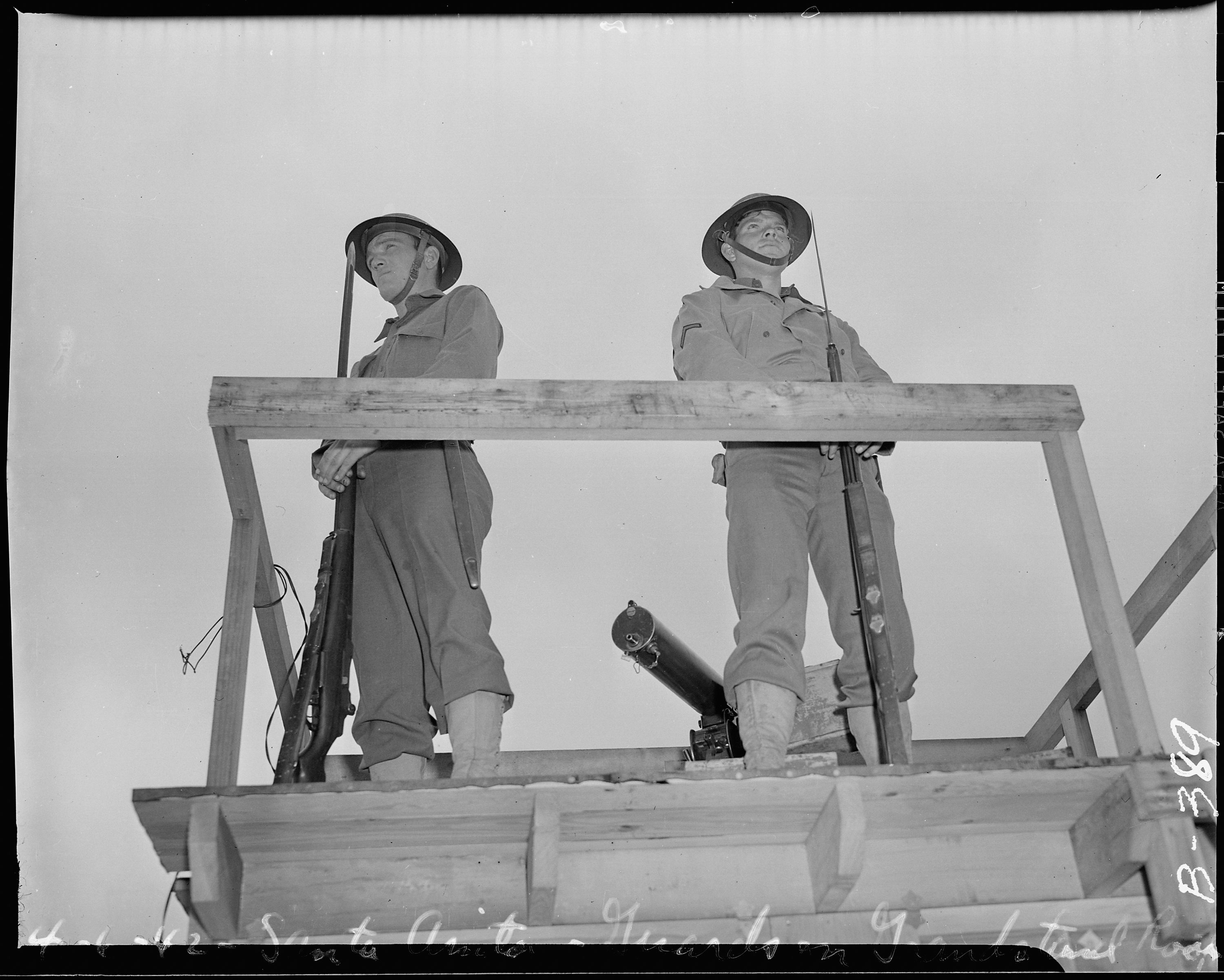 Two soldiers stand in a guard tower.