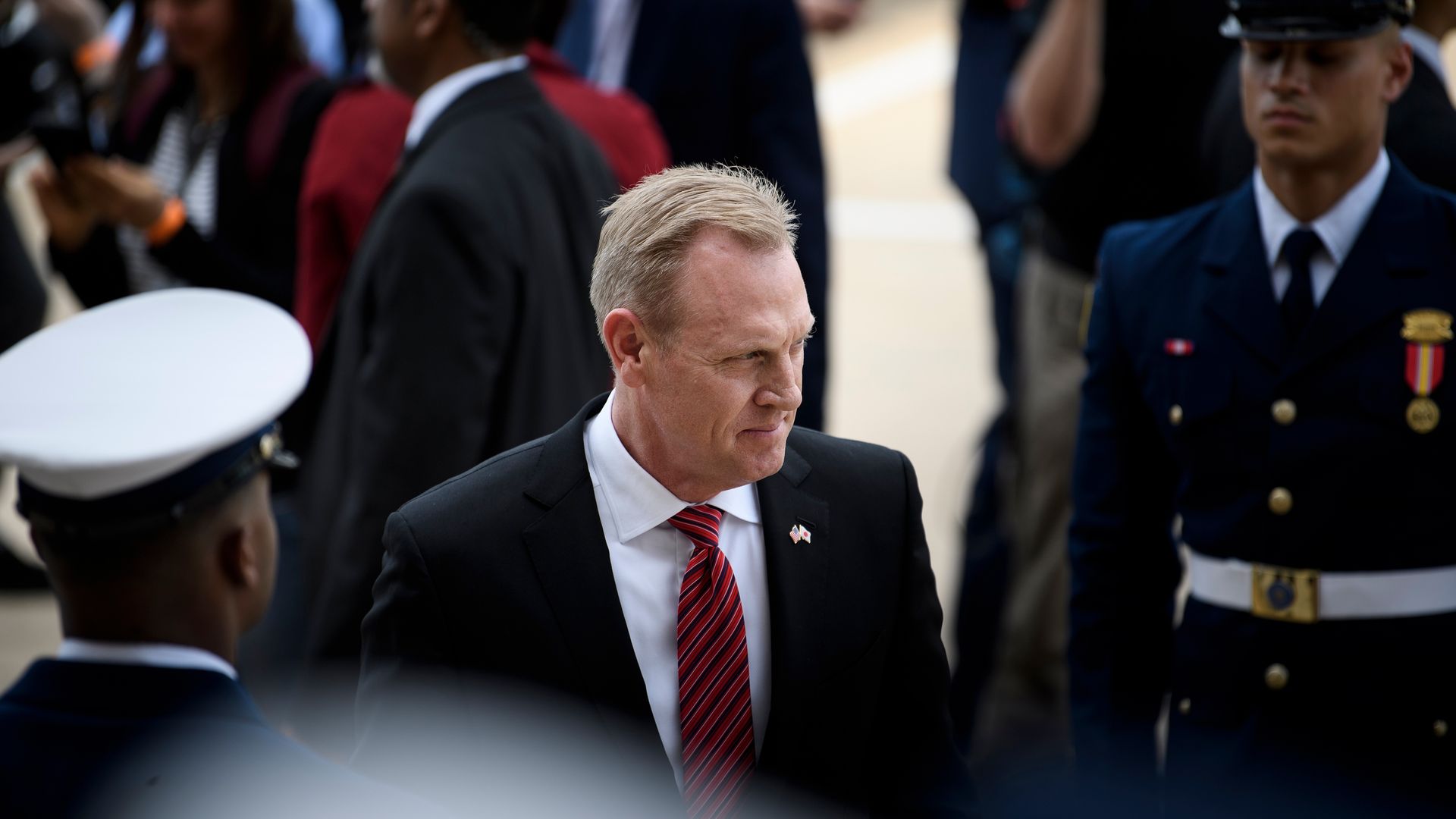 Acting Defense secretary Patrick Shanahan walks past troops in uniform.