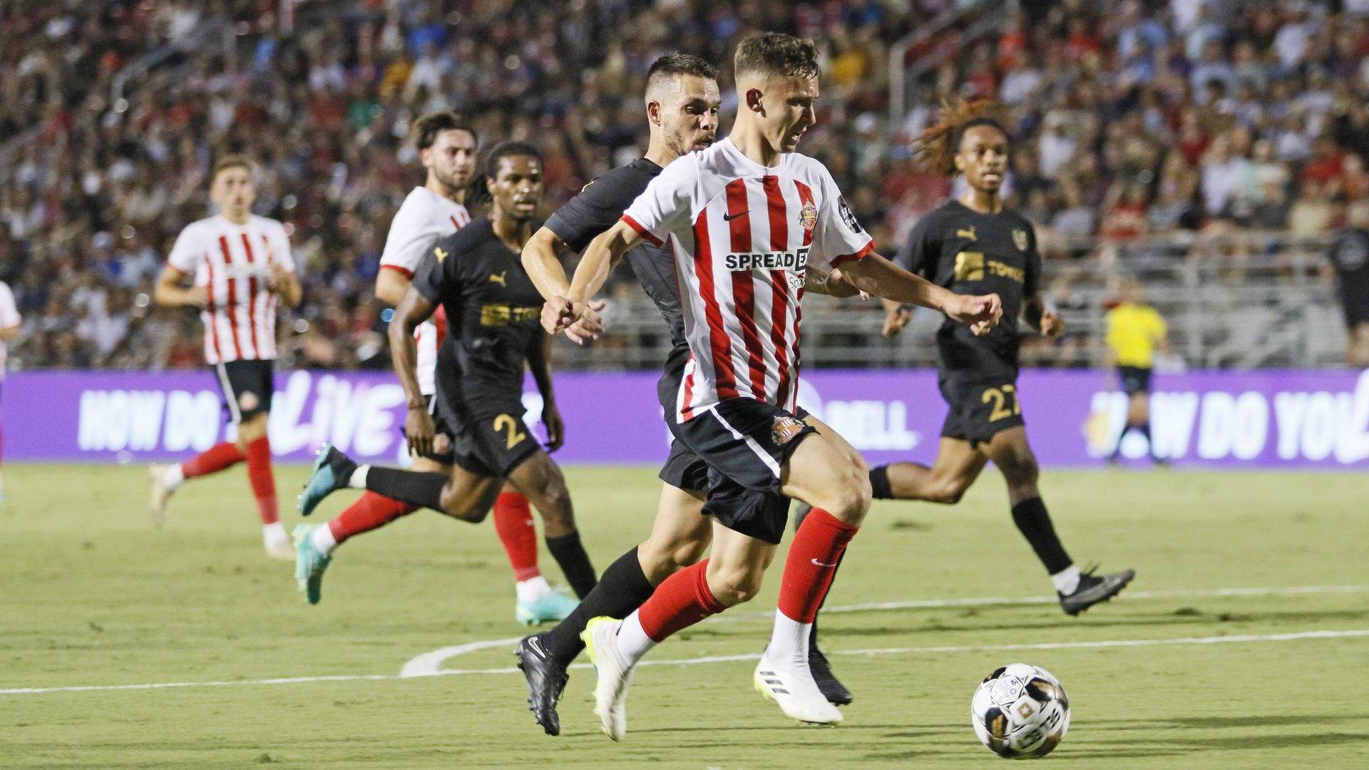 Soccer players from two teams going after the ball.