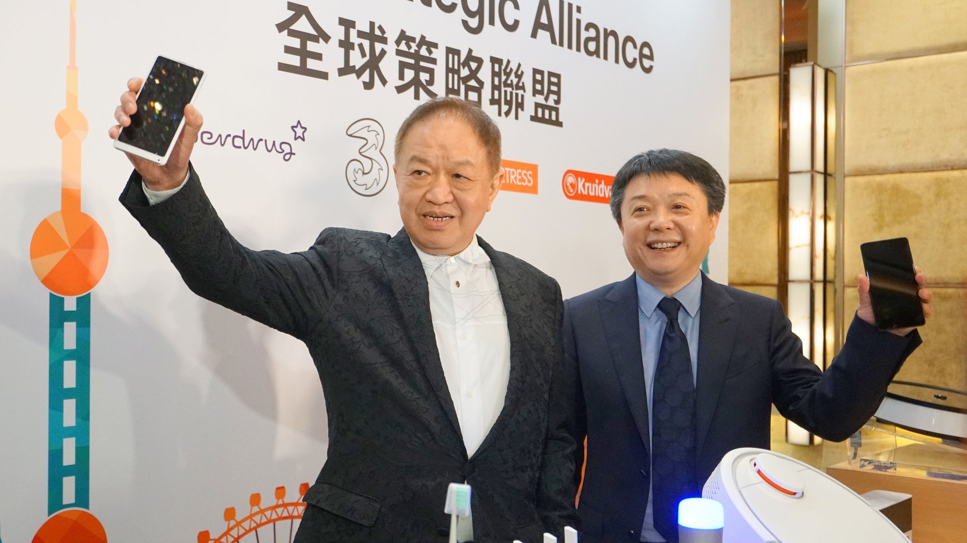 Canning Fok (L), group co-managing director of CK Hutchison, holds up a phone. He stands next to Wang Xiang, senior vice president of Xiaomi.