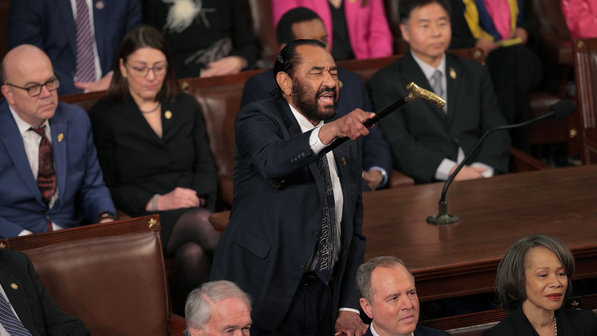 Al Green, standing up on the House floor, pointing his finger at the president while other lawmakers sit