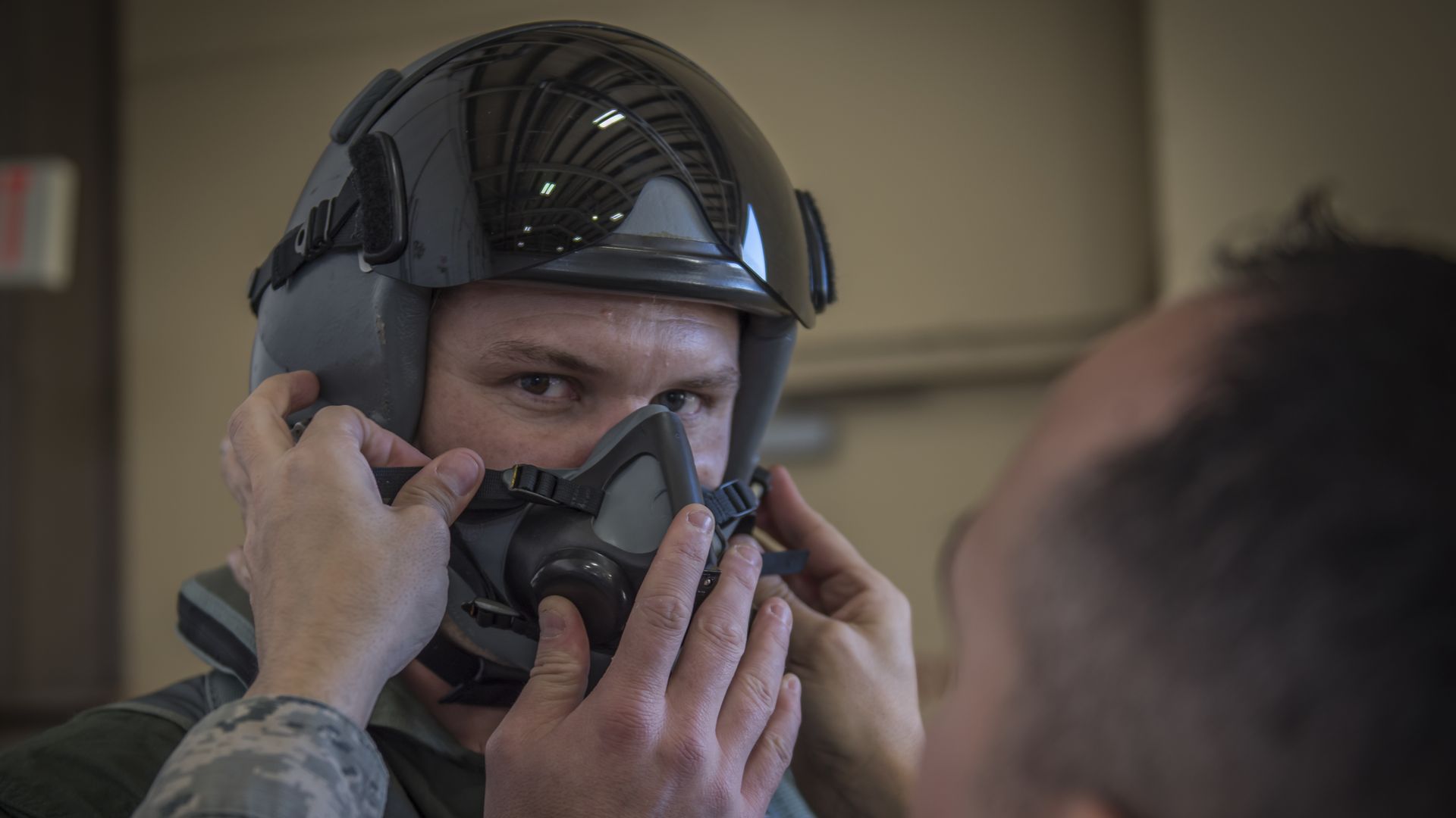 Pete Hegseth, now defense secretary, wearing a flight suit and mask. Another man helps him with fitting.