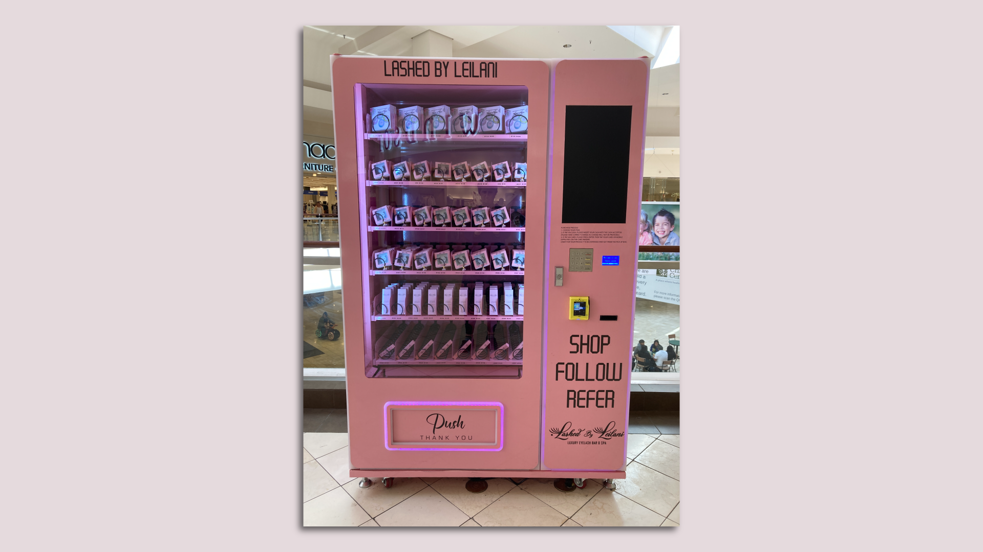 A pink vending machine, with rows of false eyelashes and accessories visible through the glass.