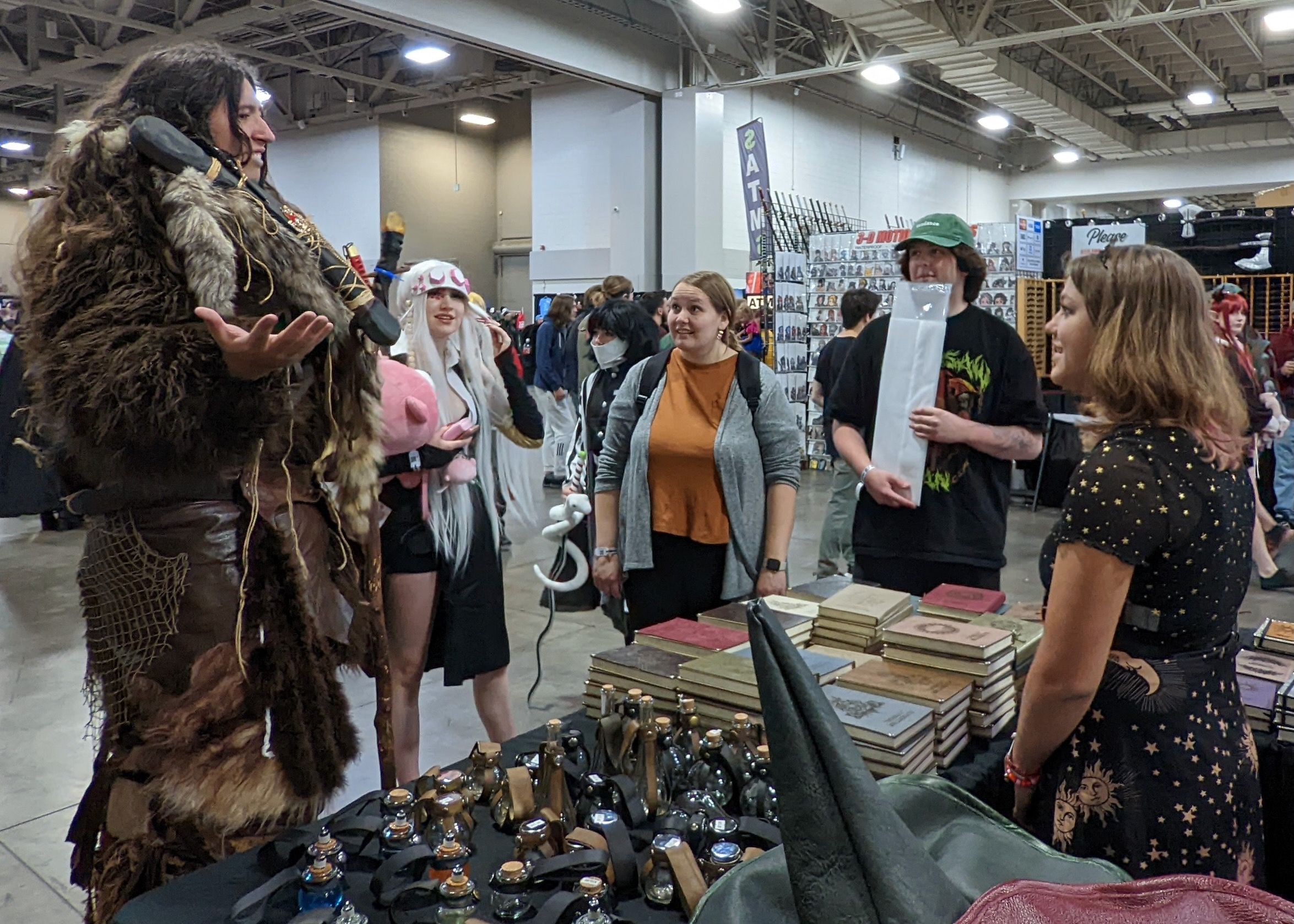 A group of people admire a man's costume of furs at a fan convention.