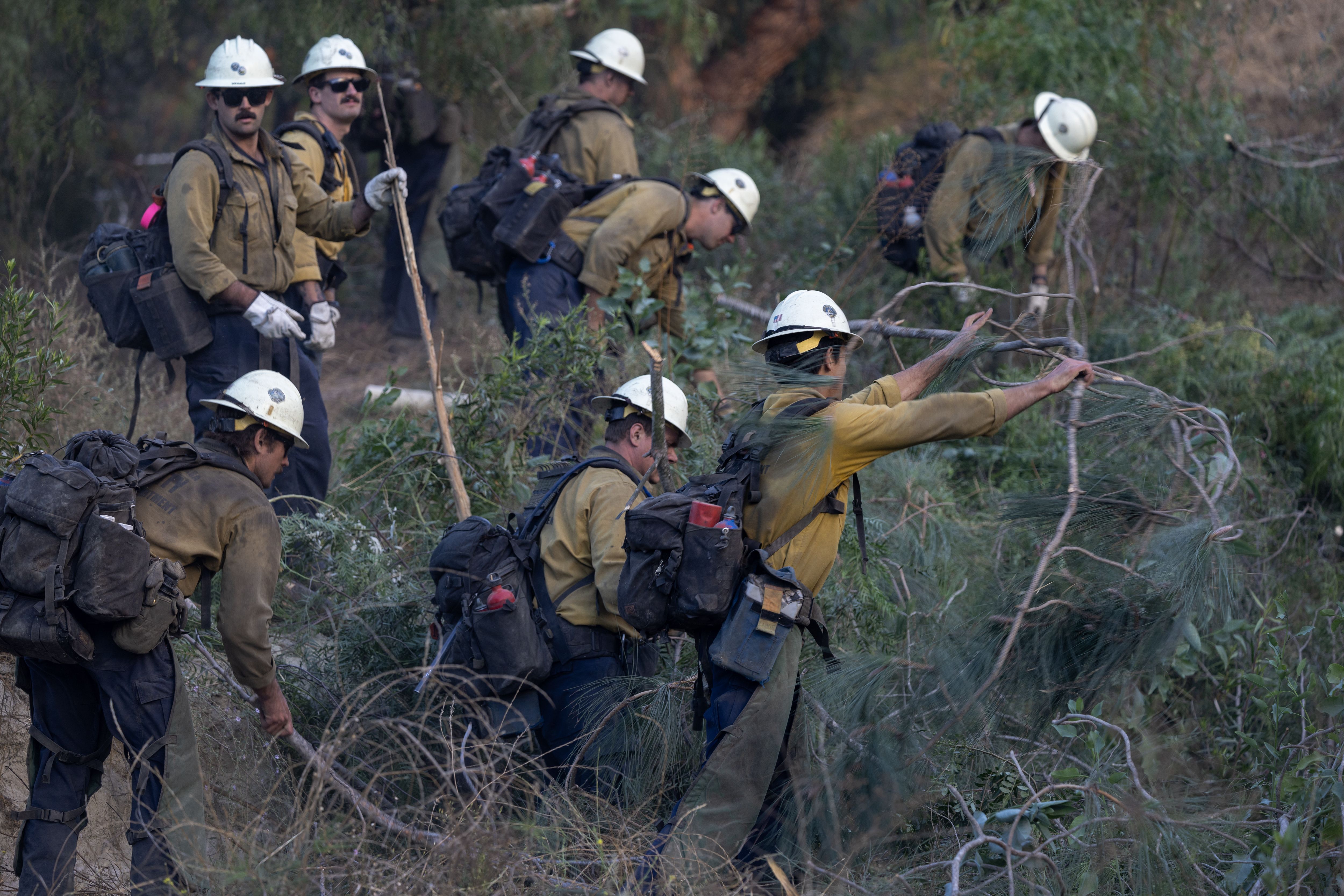 Firefighters clear vegetation to protect a ranch house at the Mountain Fire on November 7, 2024 near Fillmore, California. 