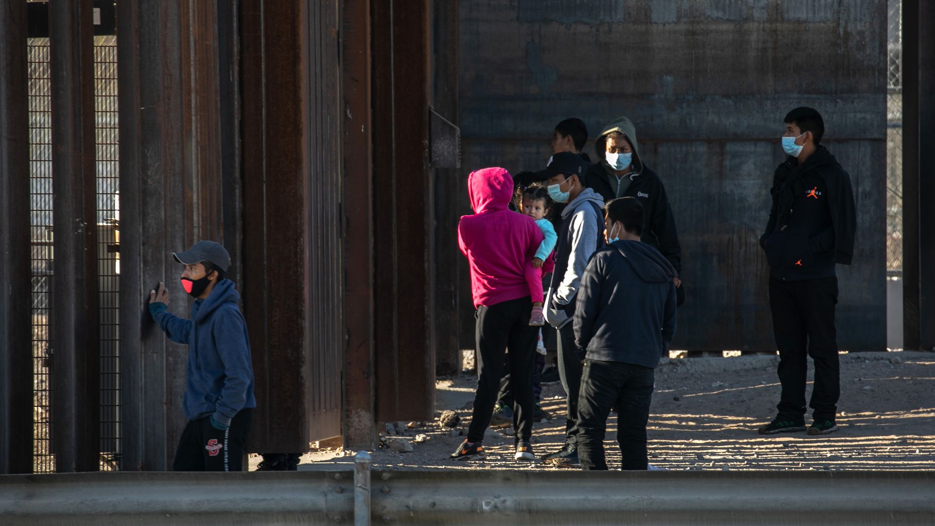 Undocumented immigrants stand next to the border wall while waiting for U.S. Border Patrol agents to arrive