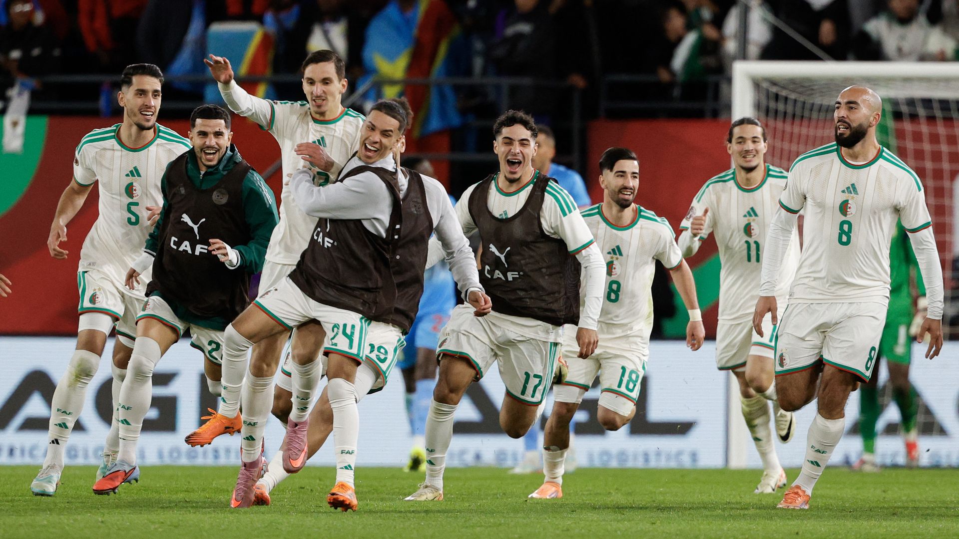 Eight soccer team members celebrate on a field.