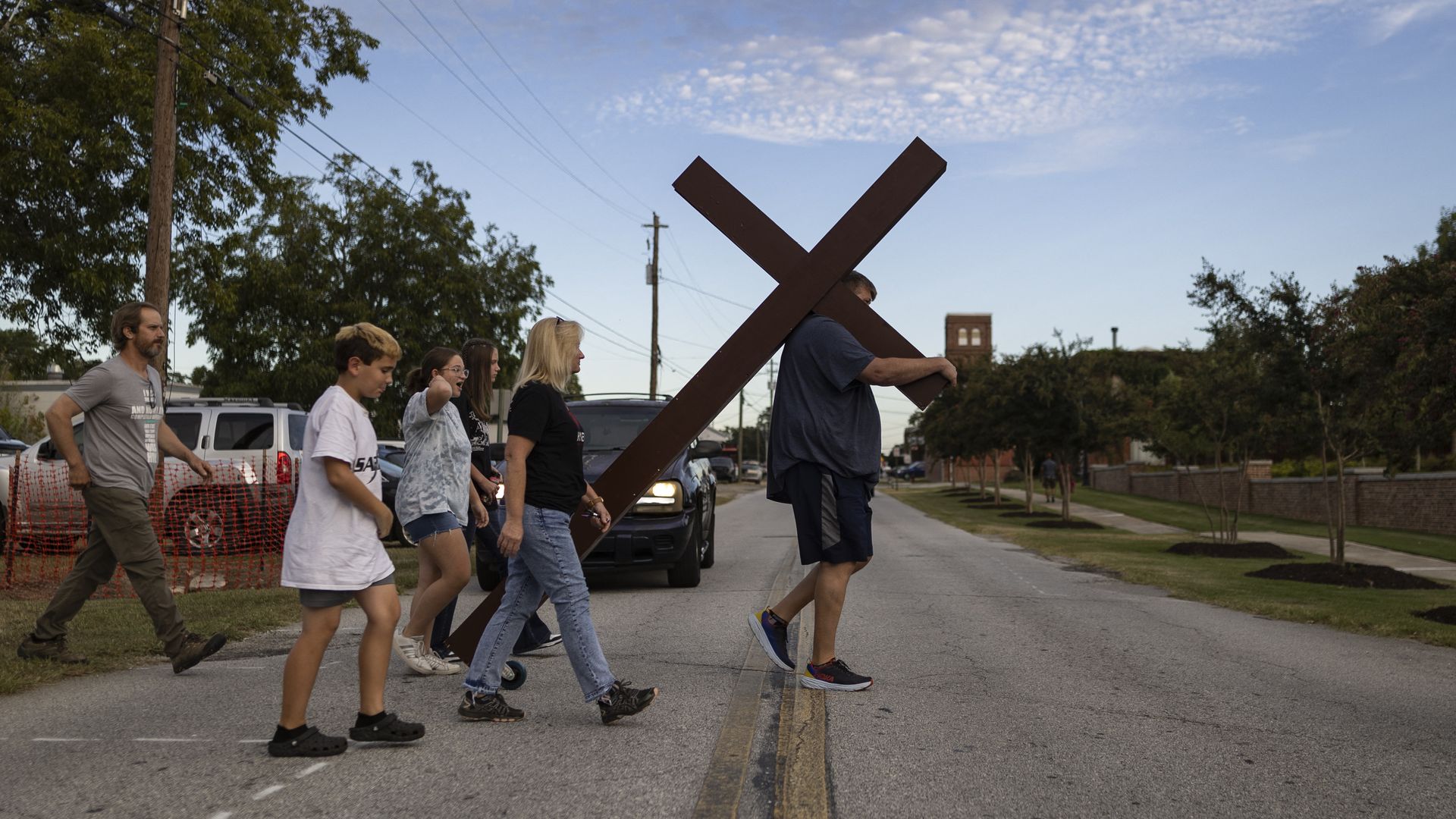 A man carries a large cross to a vigil for the Apalachee High School shooting at Jug Tavern Park in Winder, Georgia, on September 4, 2024.