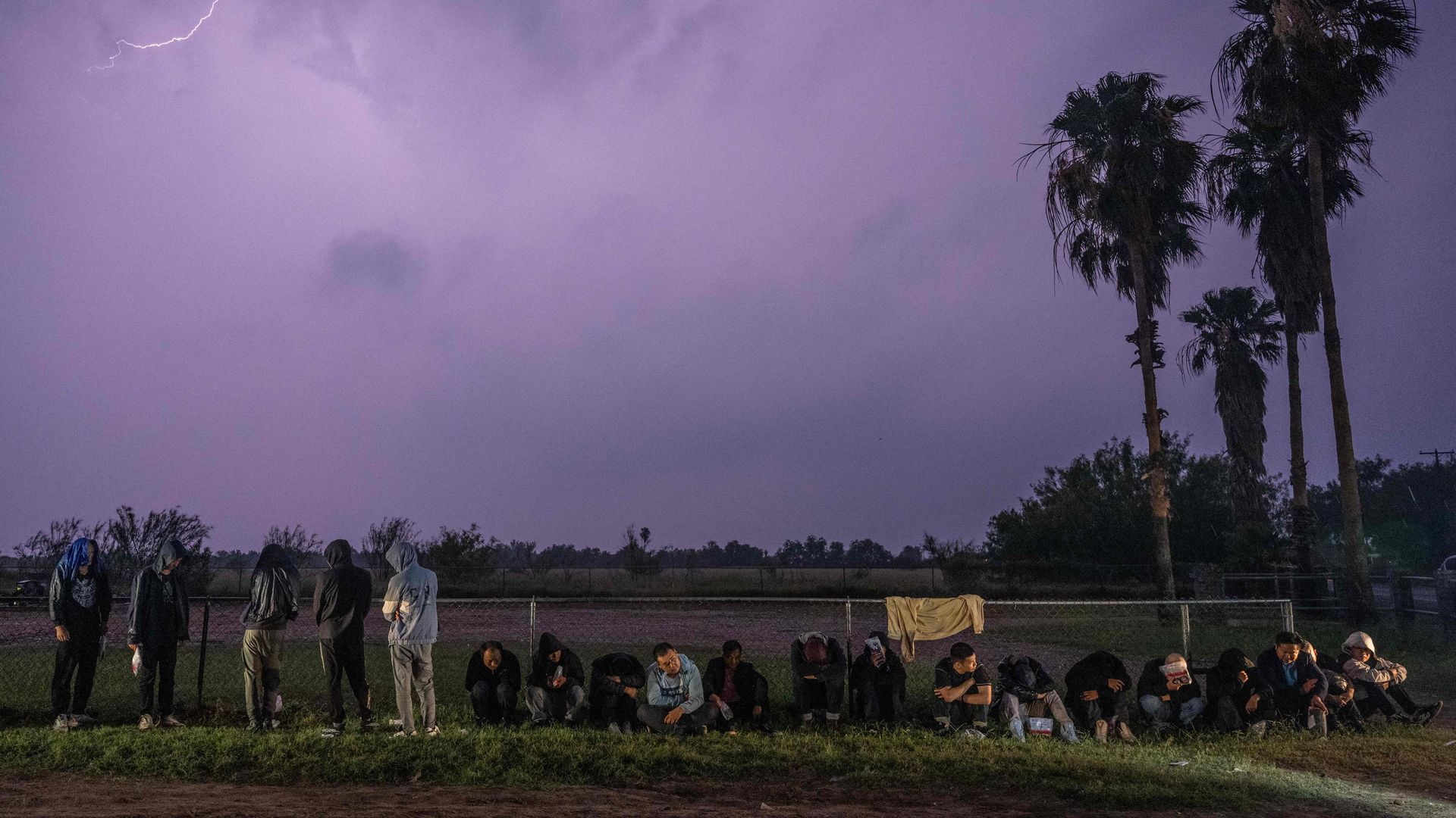 Migrants wait in the rain after turning themselves over to US Border Patrol agents after crossing over from Mexico in Fronton, Texas 