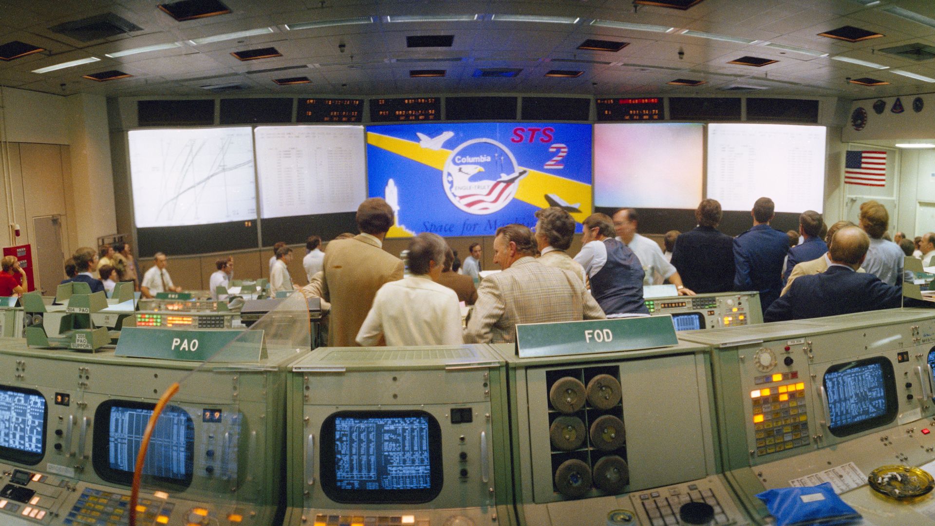 Photo of computers and projector screen inside mission control. 