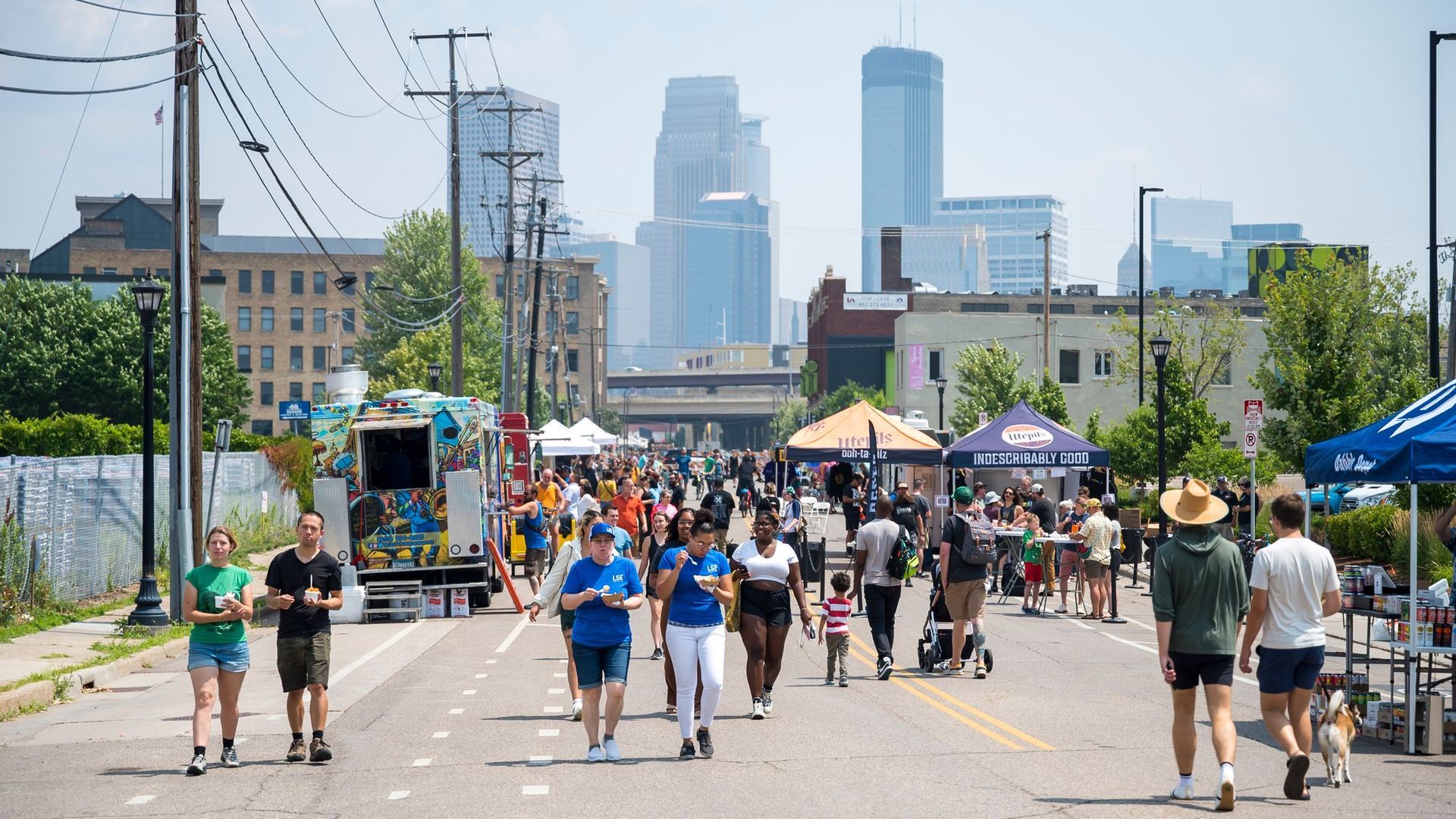 A group of people at a street fest taking place against the backdrop of a city skyline