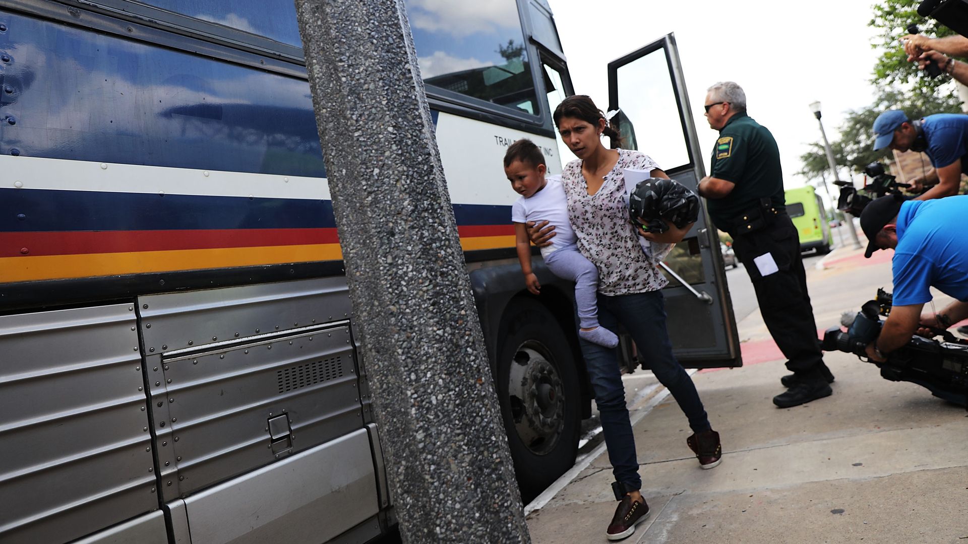 A migrant woman and her child get off a bus