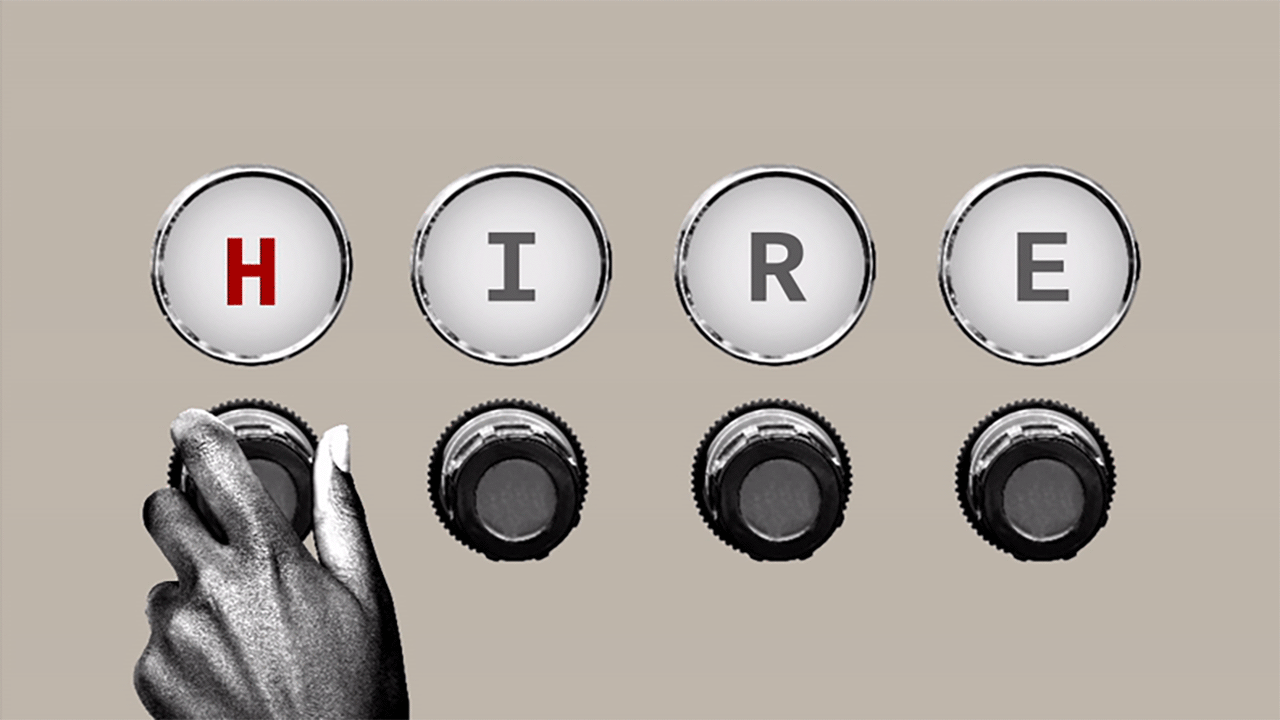 The word HIRE on a machine with knobs, a hand is turning the first knob changing the H to an F, so it reads FIRE.