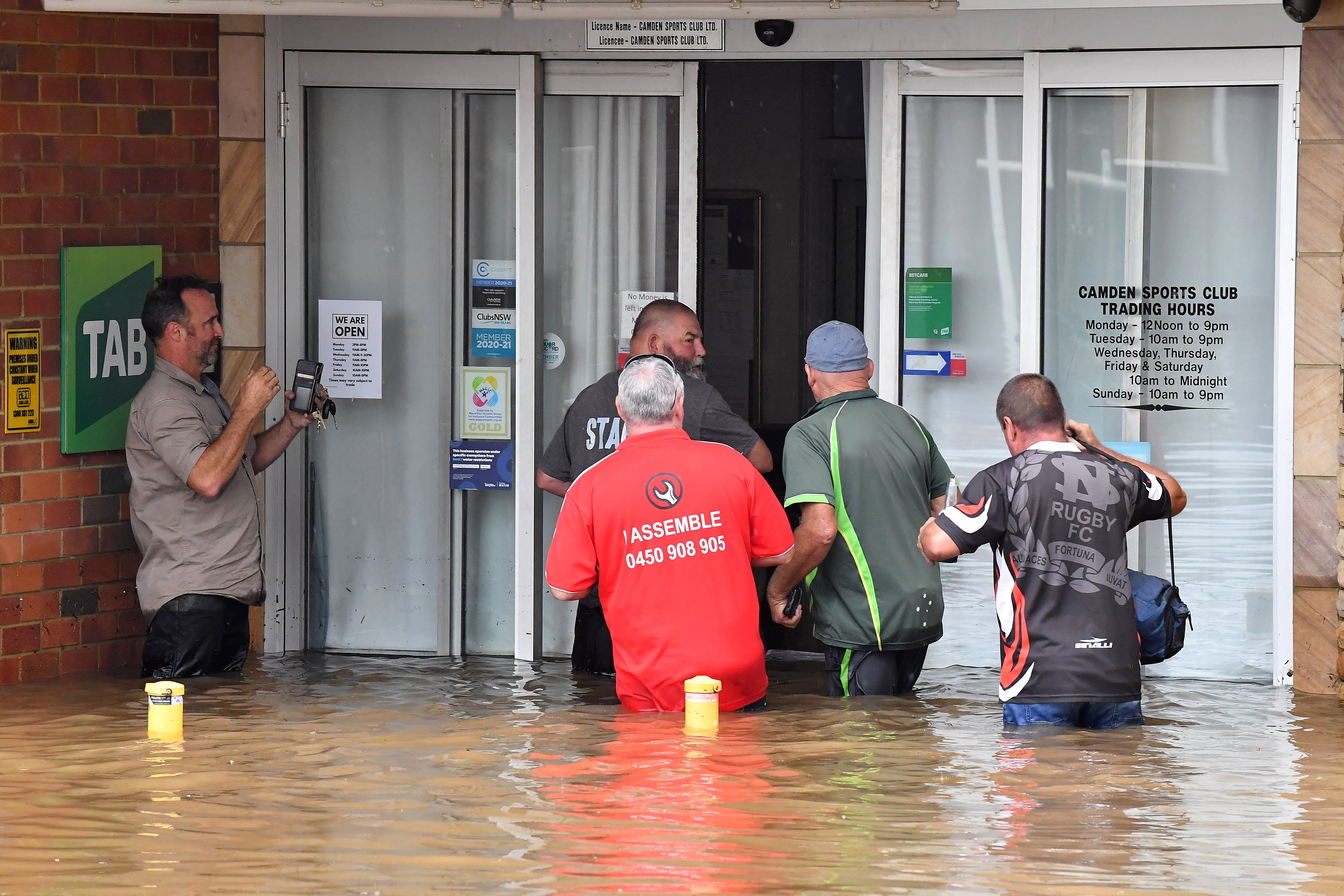 AUSTRALIA-WEATHER-FLOOD Staff of the Camden Sports Club wade through the floodwaters to enter into the building in southwestern Camden suburb of Sydney on March 8