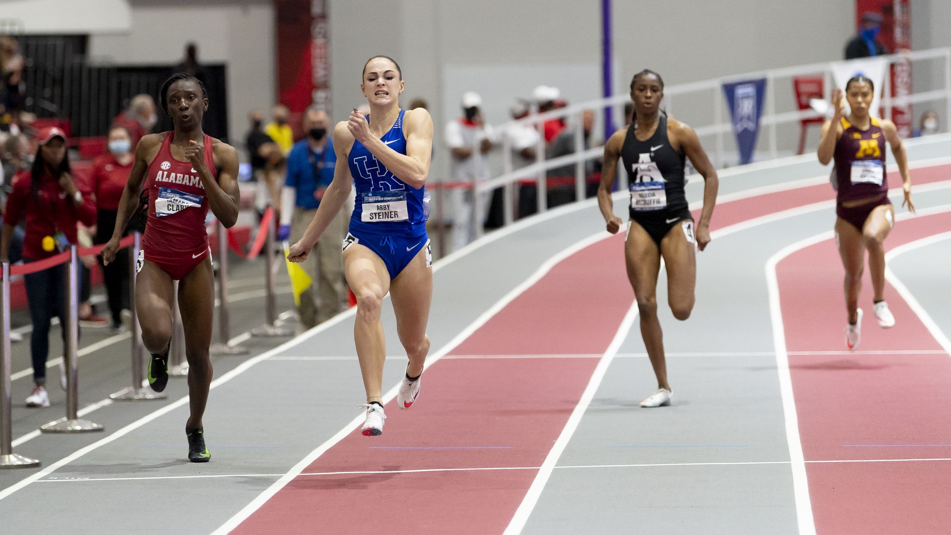 Three sprinters in an indoor track. 