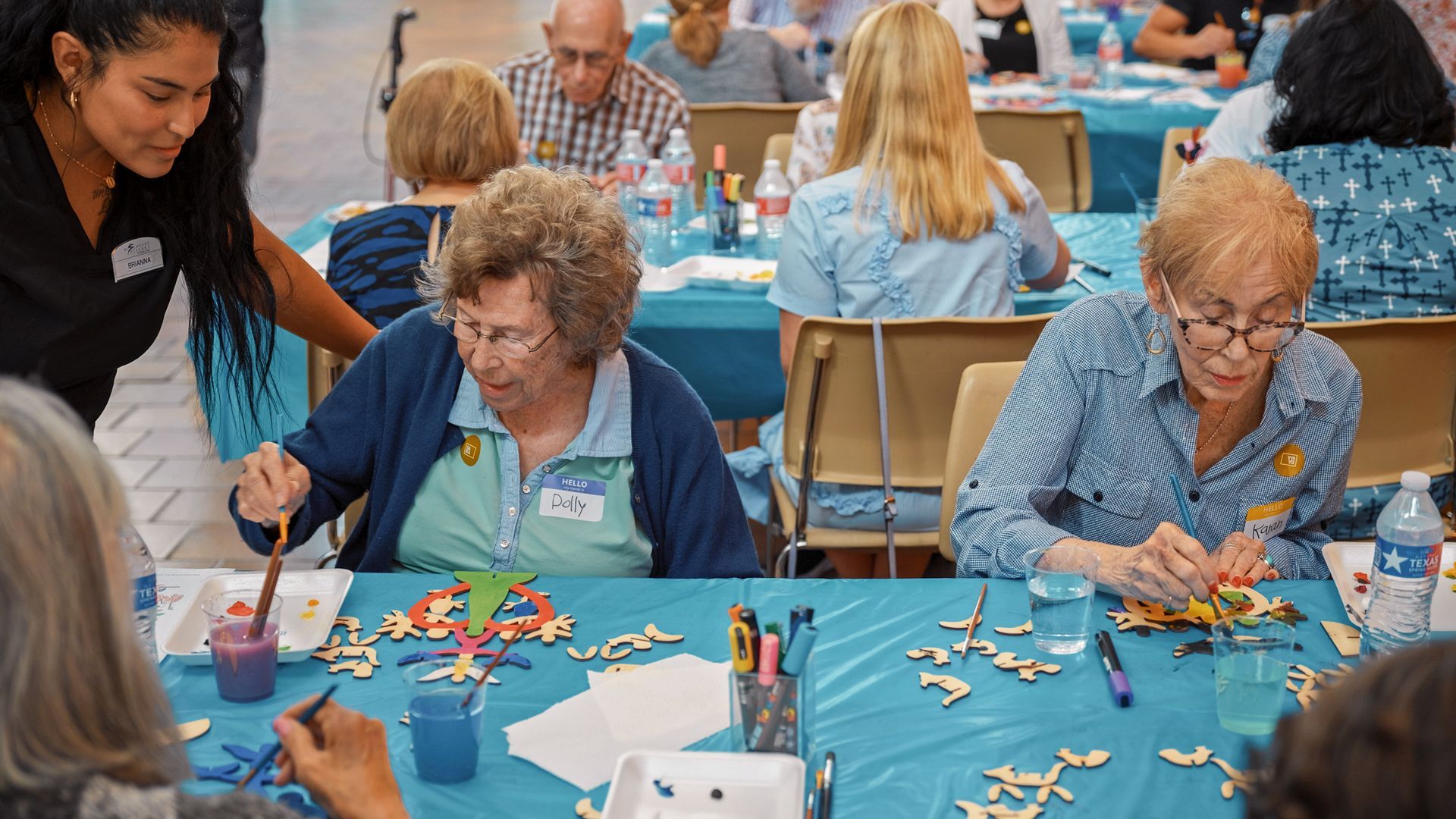 Two older women sitting at a variety of tables painting 