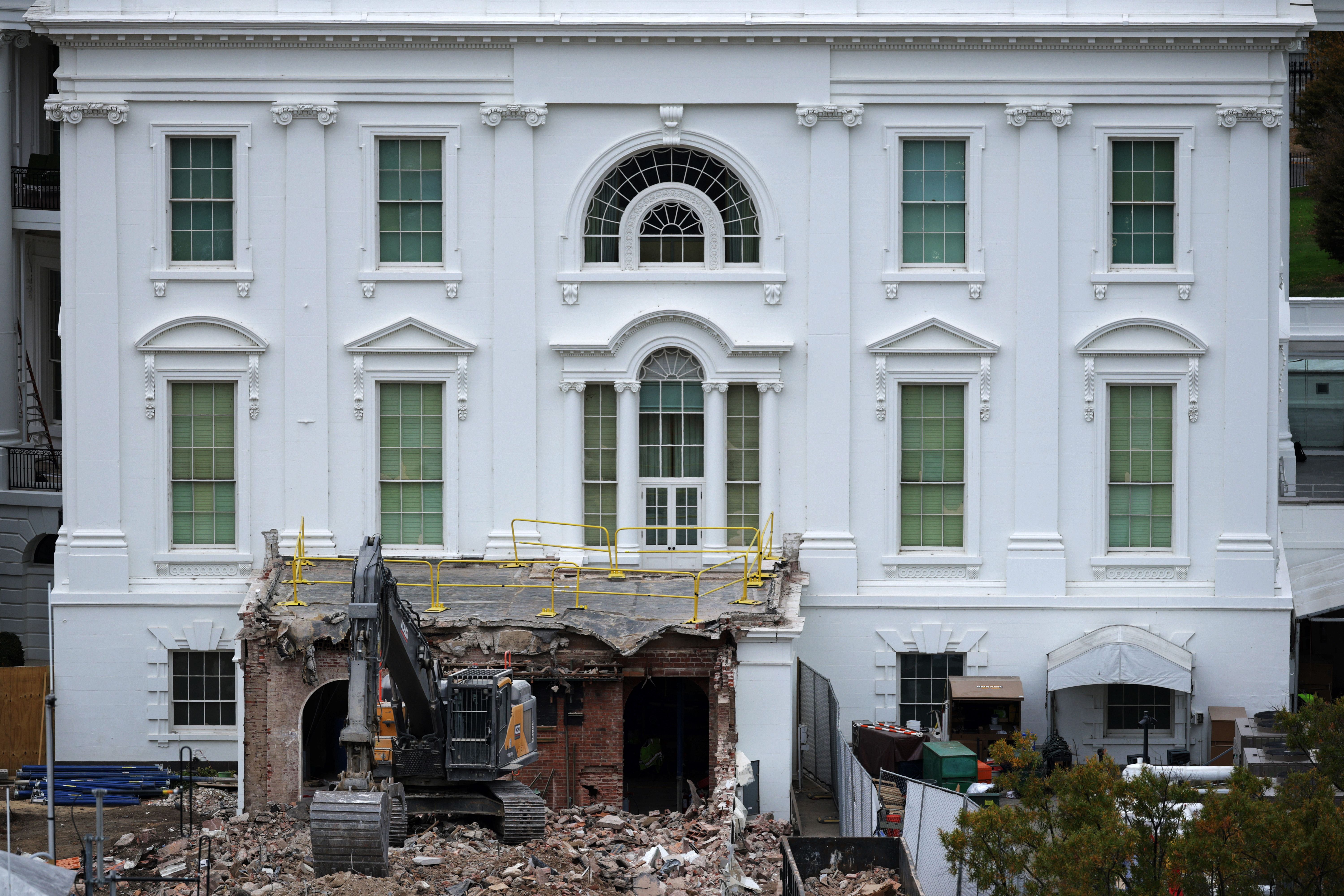 The white facade of the White House where East Wing was attached, with wreckage where that part of the building connected to the house. 