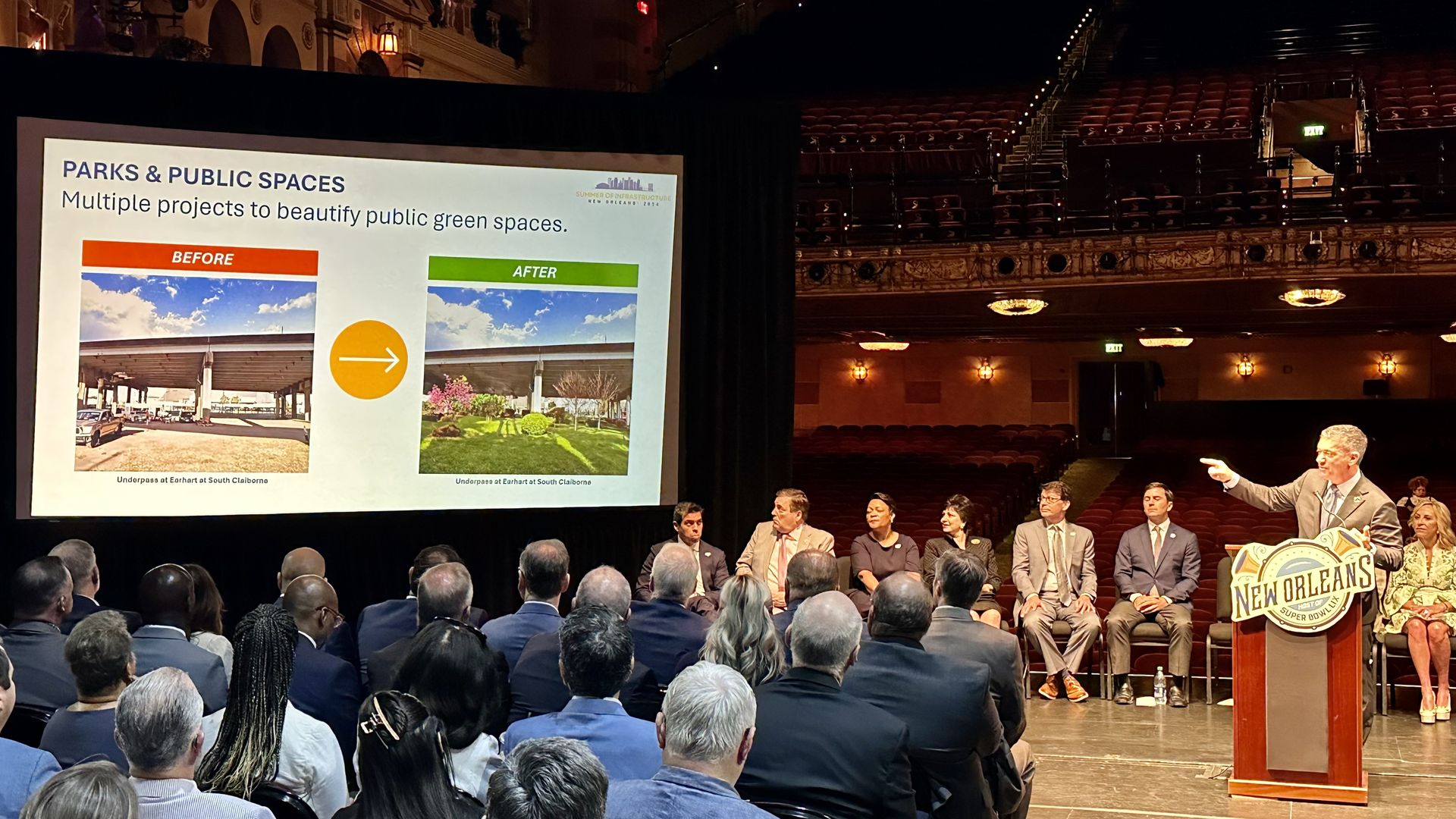 Photo shows Michael Hecht standing behind a podium and pointing to a screen showing before and after pictures of a beautified park area.