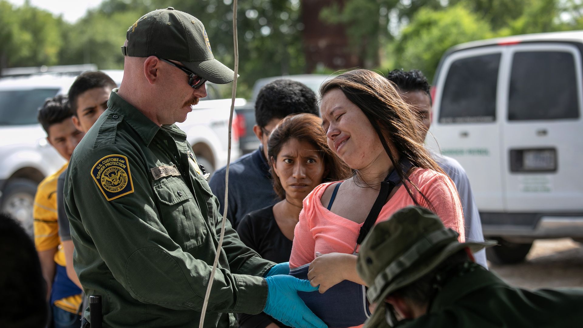 A border patrol officer checks a migrant's arm which is in a cast. 
