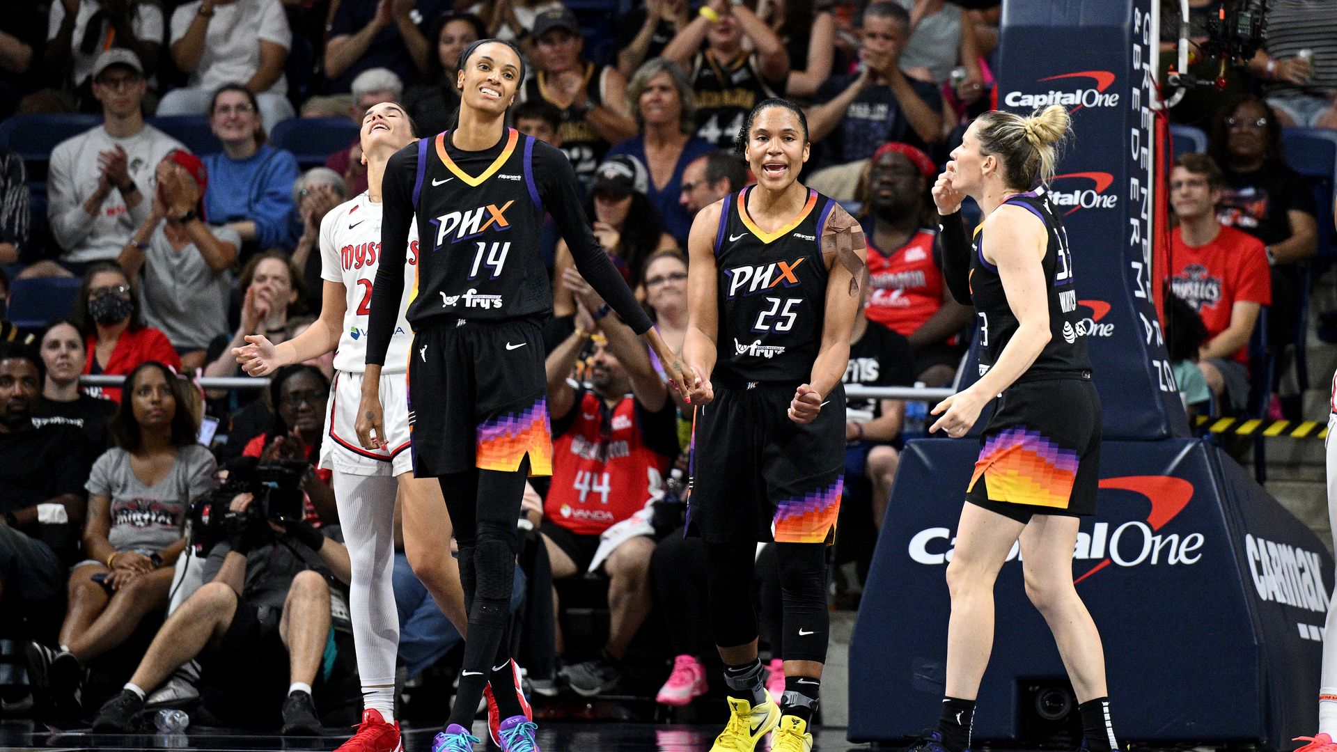 Phoenix Mercury players Alyssa Thomas, DeWanna Bonner and Sami Whitcomb celebrate on a basketball court, with a crowd in the background.
