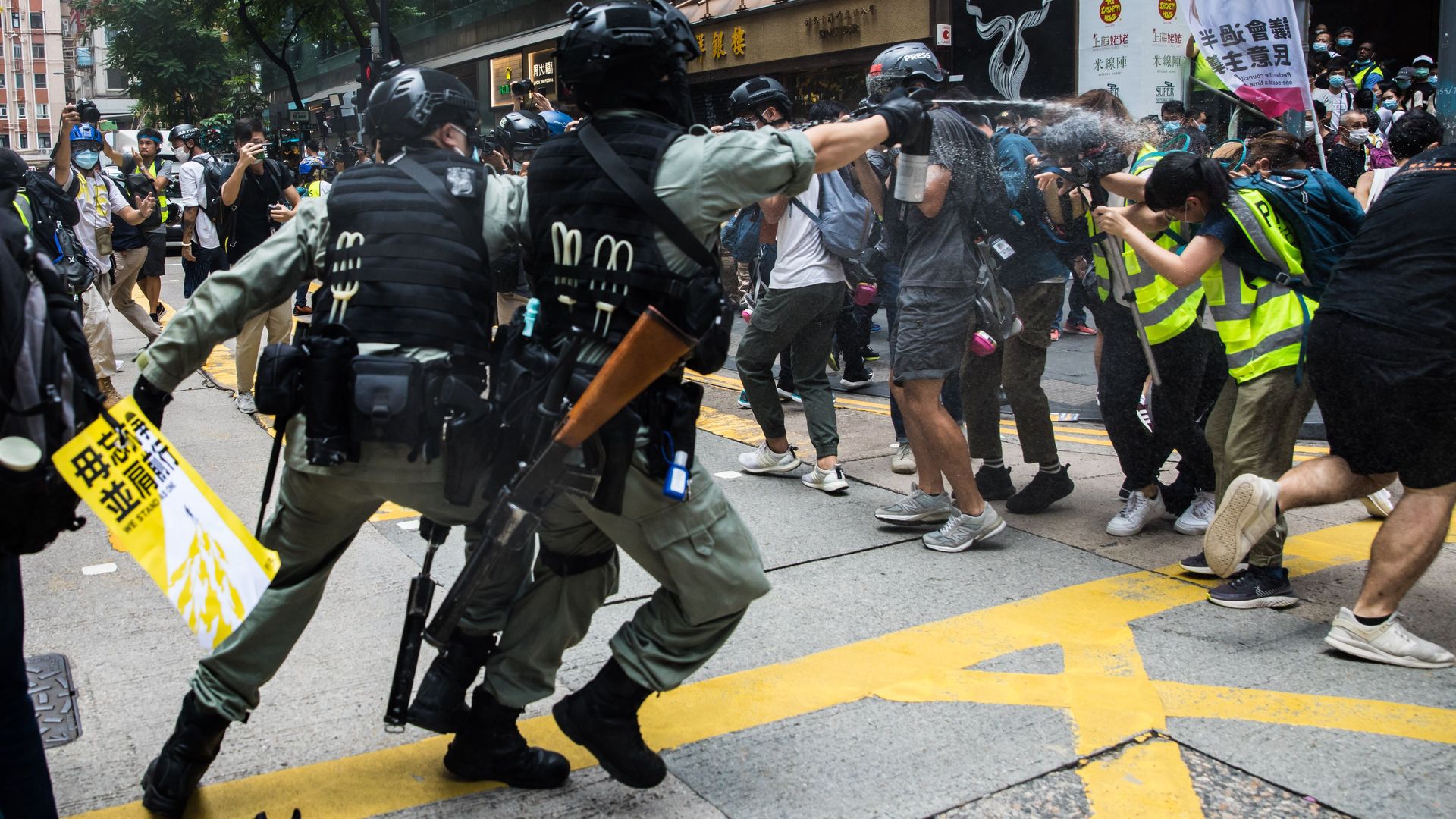 Riot police (L) deploy pepper spray toward journalists (R) as protesters gathered for a rally against a new national security law in Hong Kong