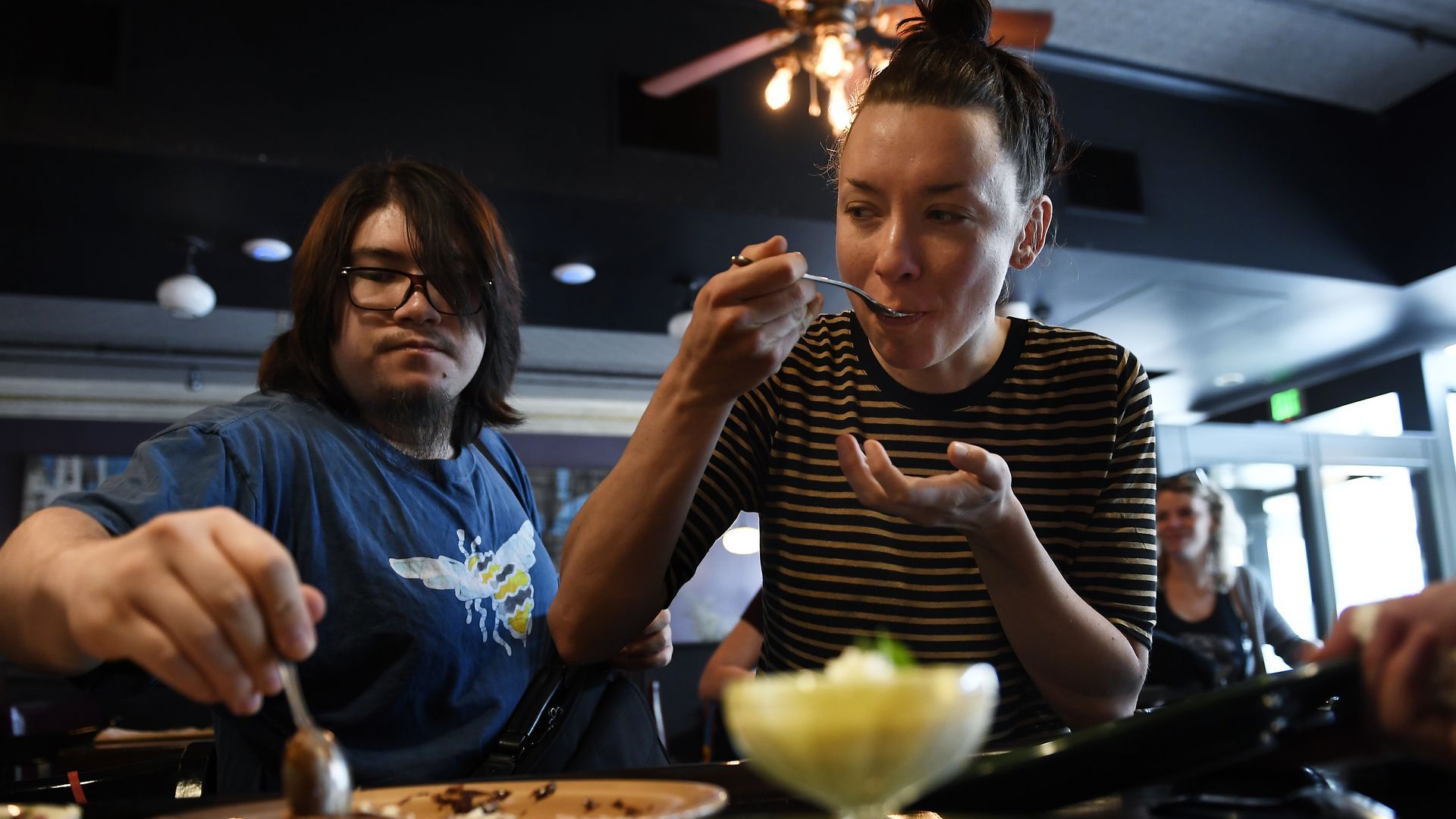 A photo of two people trying bites to eat at a restaurant