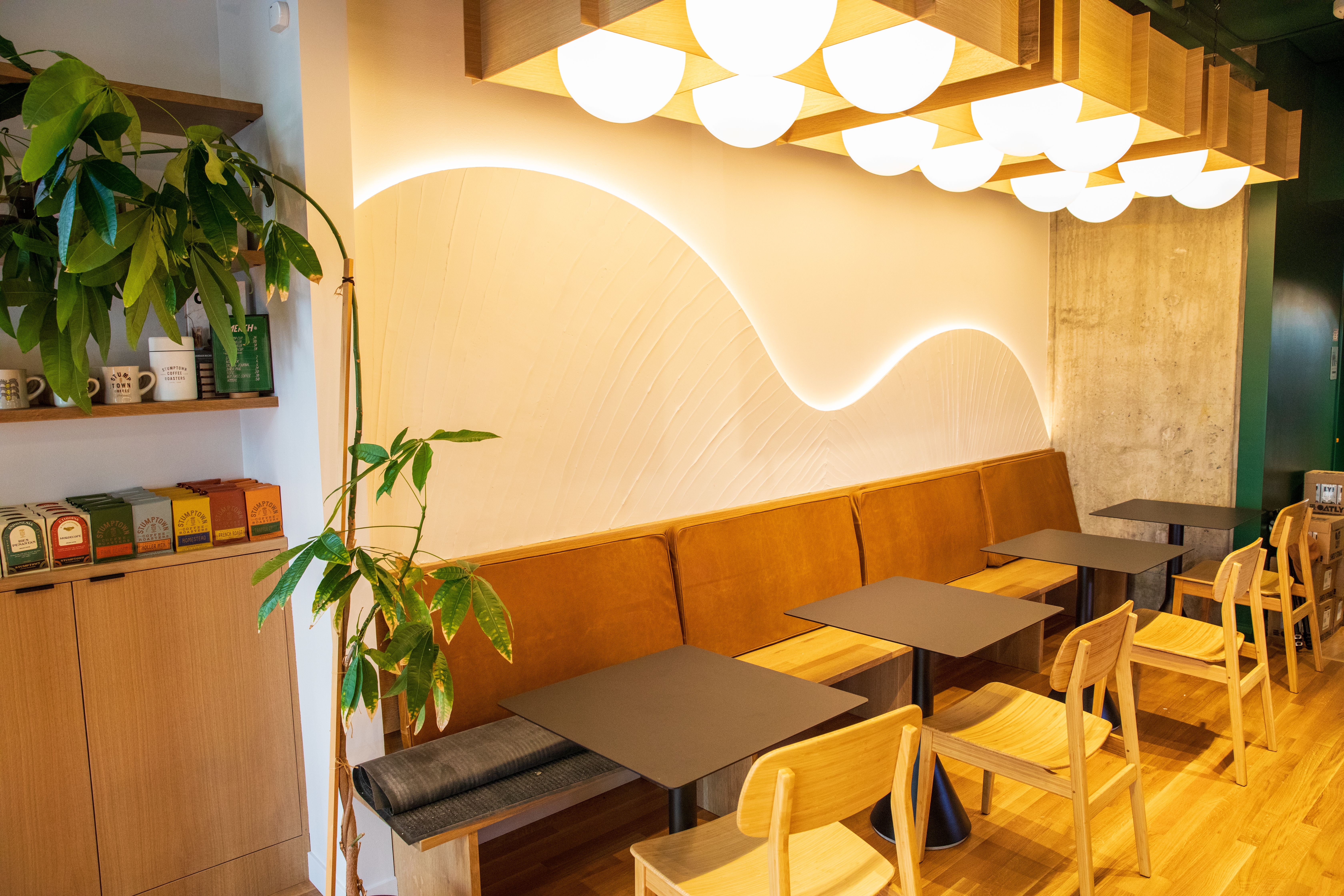A photo of a cafe with a swiggly light installation along the backside wall with tables and chairs.