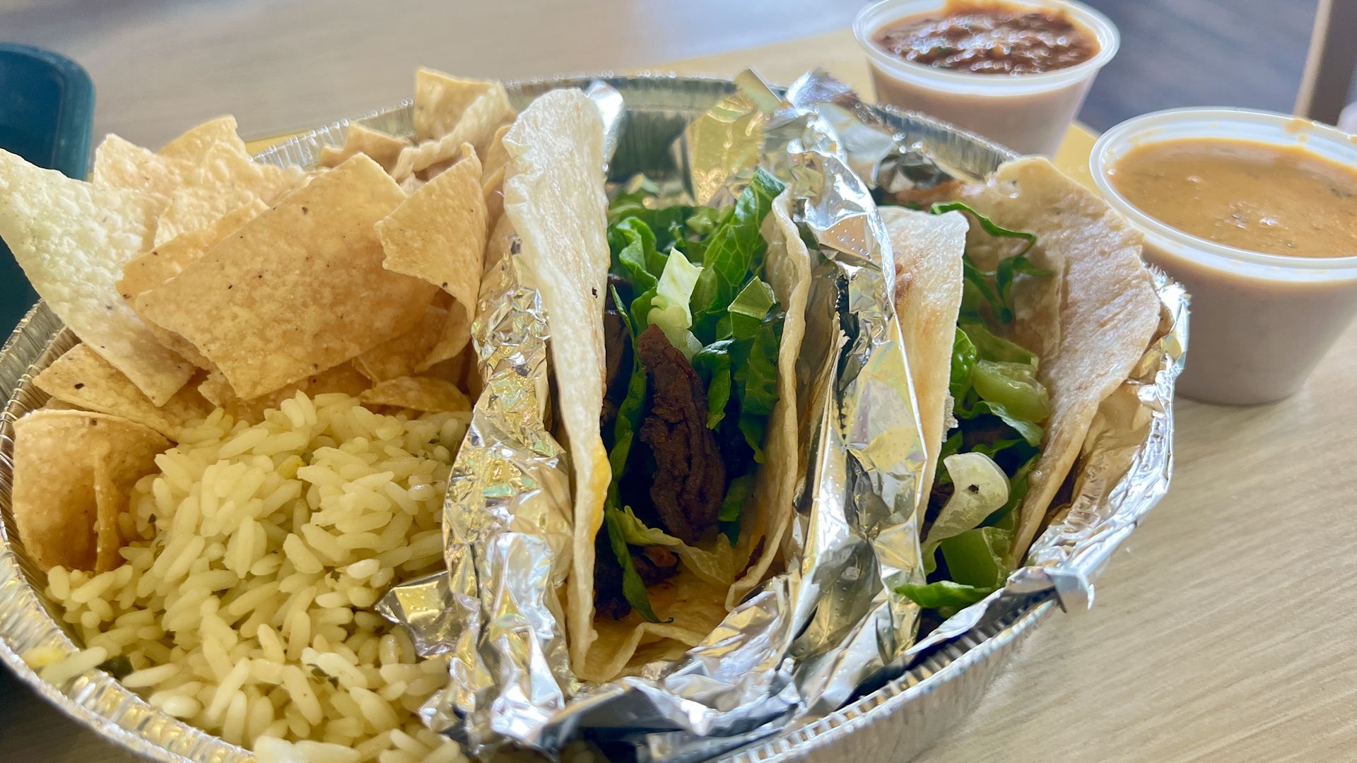 Two tacos with rice, chips and queso